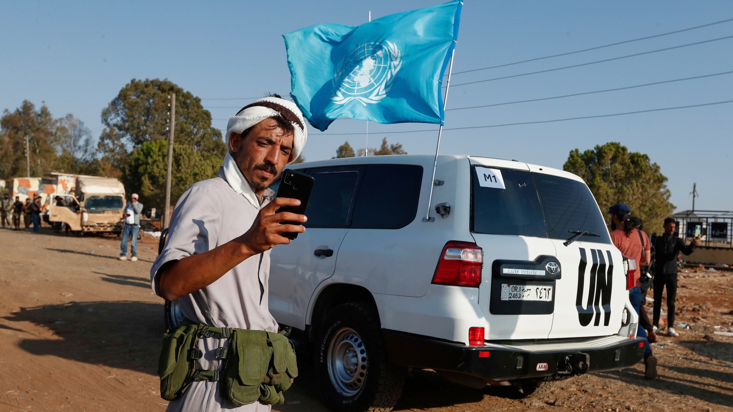 A Bedouin fighter takes a selfie in front of a U.N. vehicle as a convoy of ambulances and buses arrives at a checkpoint in the village of Busra al-Harir, southern Syria, on its way to Sweida province, as security forces cordon off the area to block Bedouin fighters from entering the province, Tuesday, July 22, 2025. (AP Photo/Omar Sanadiki)