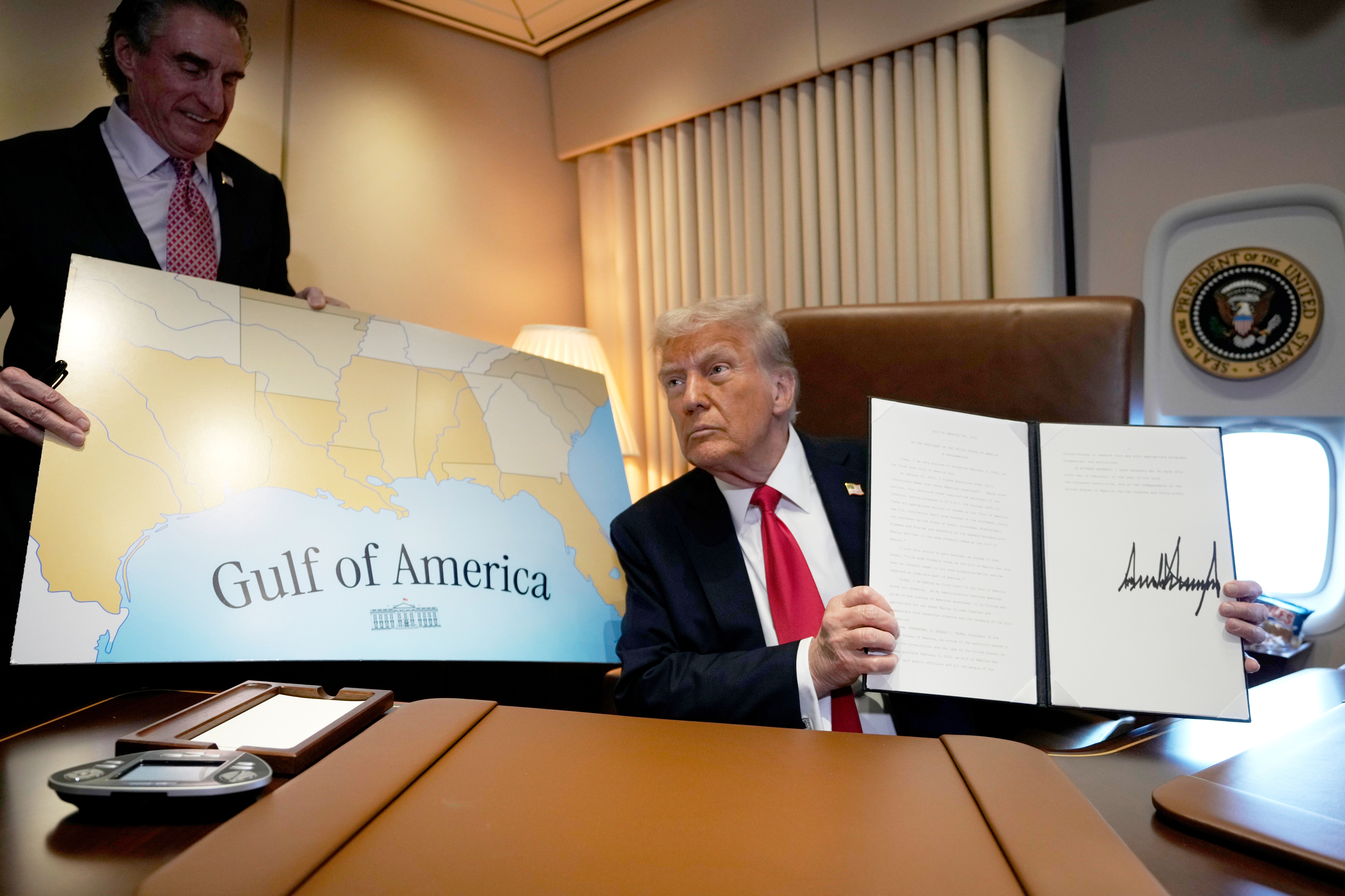 FILE - President Donald Trump holds up a signed proclamation declaring Feb. 9 Gulf of America Day, as Interior Secretary Doug Burgum watches aboard Air Force One as Trump travels from West Palm Beach, Fla. to New Orleans, Feb. 9, 2025. (AP Photo/Ben Curtis, File)