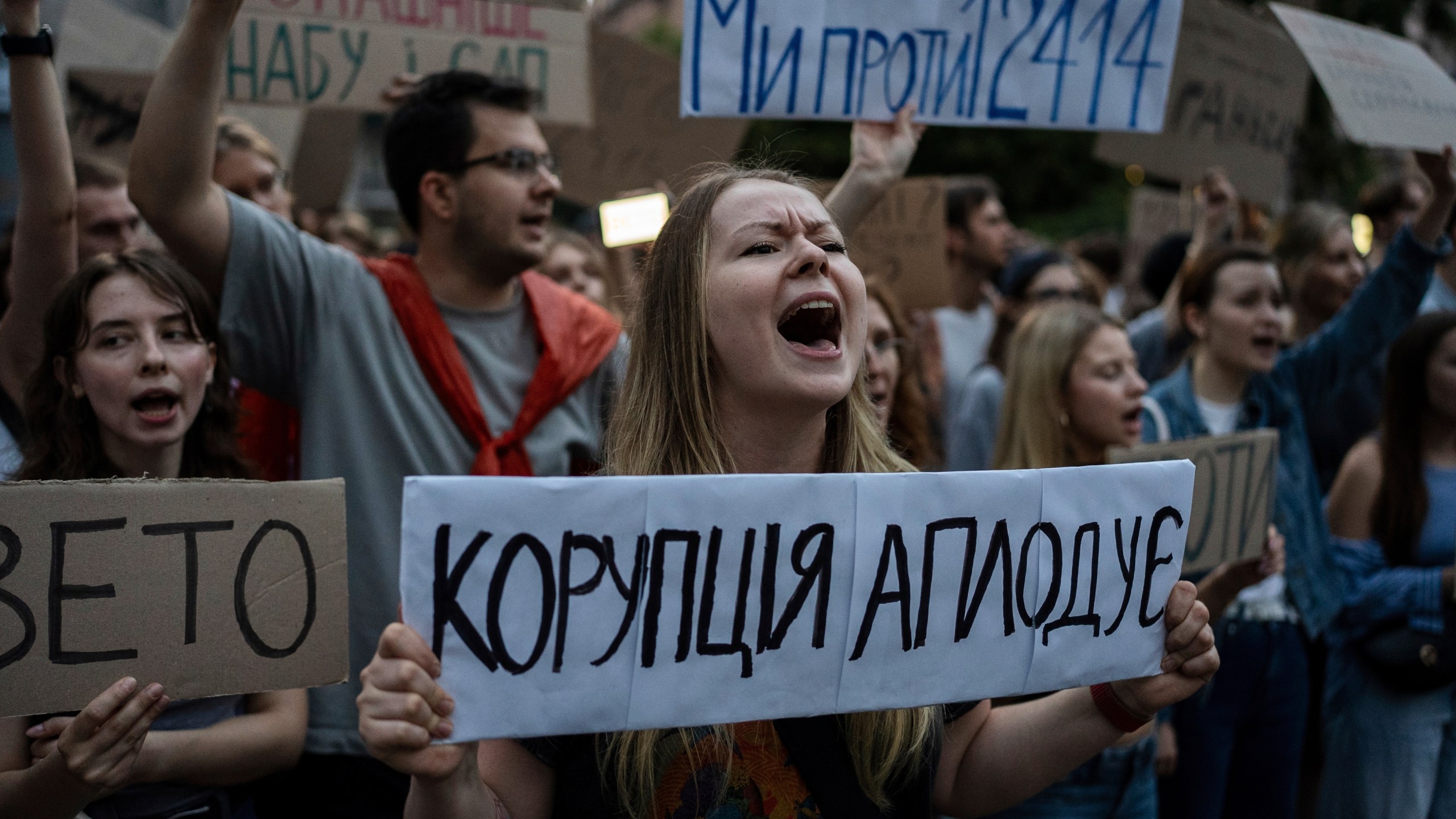 A woman chants while holding a banner that reads, “Corruption Applauds,” during a protest against a law targeting anti-corruption institutions in central Kyiv, Ukraine, Tuesday, July 22, 2025. (AP Photo/Alex Babenko)