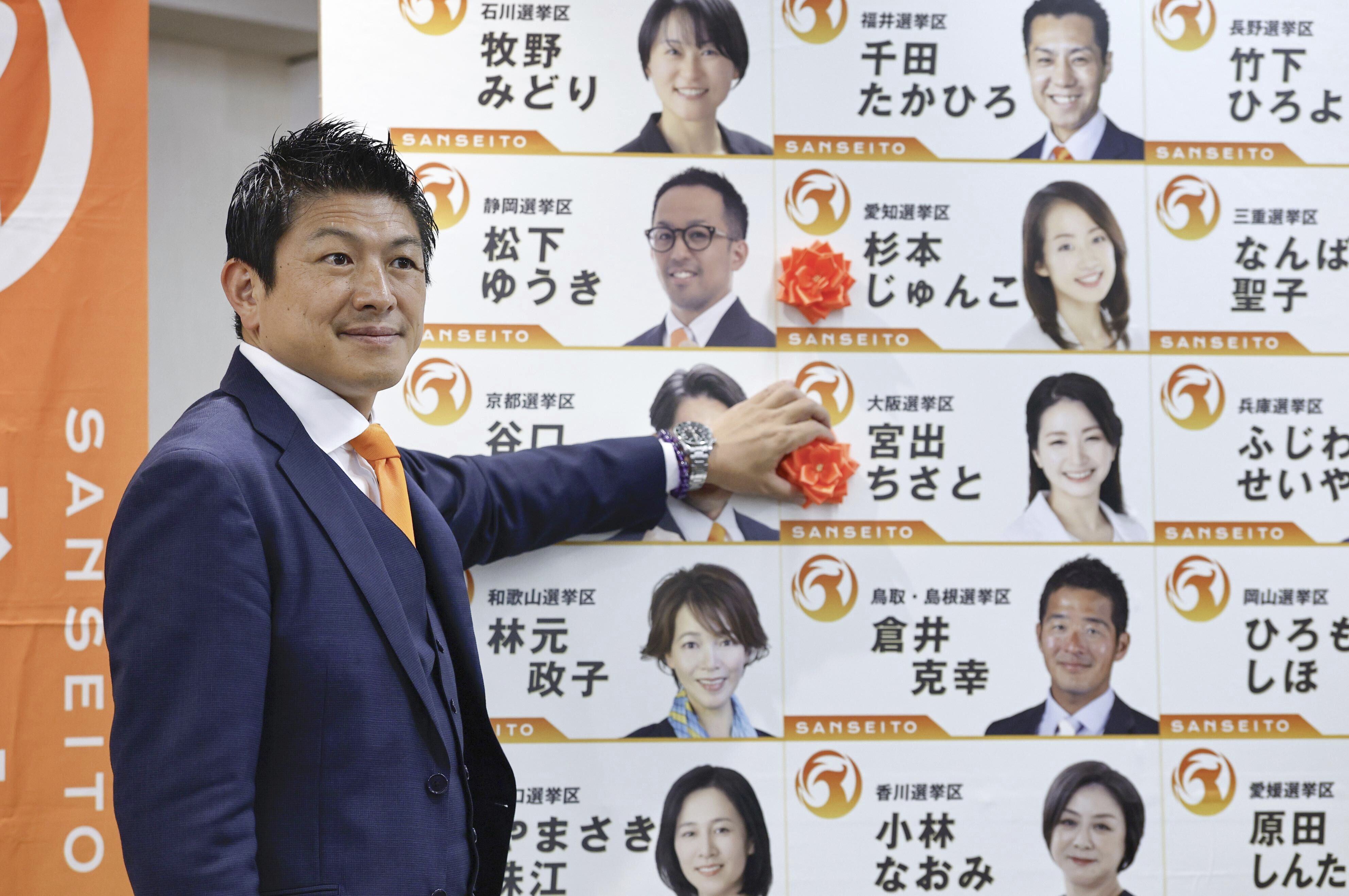 Sohei Kamiya, leader of Japan's far-right populist Sanseito party, places a red paper rose on the name of an elected candidate, in Tokyo, Sunday, July 20, 2025. (Kyodo News via AP)