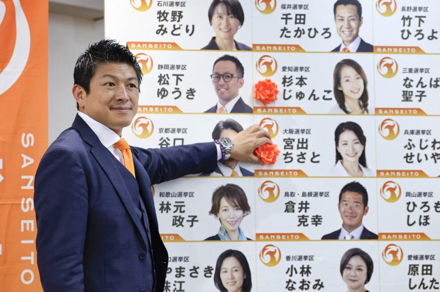 Sohei Kamiya, leader of Japan's far-right populist Sanseito party, places a red paper rose on the name of an elected candidate, in Tokyo, Sunday, July 20, 2025. (Kyodo News via AP)