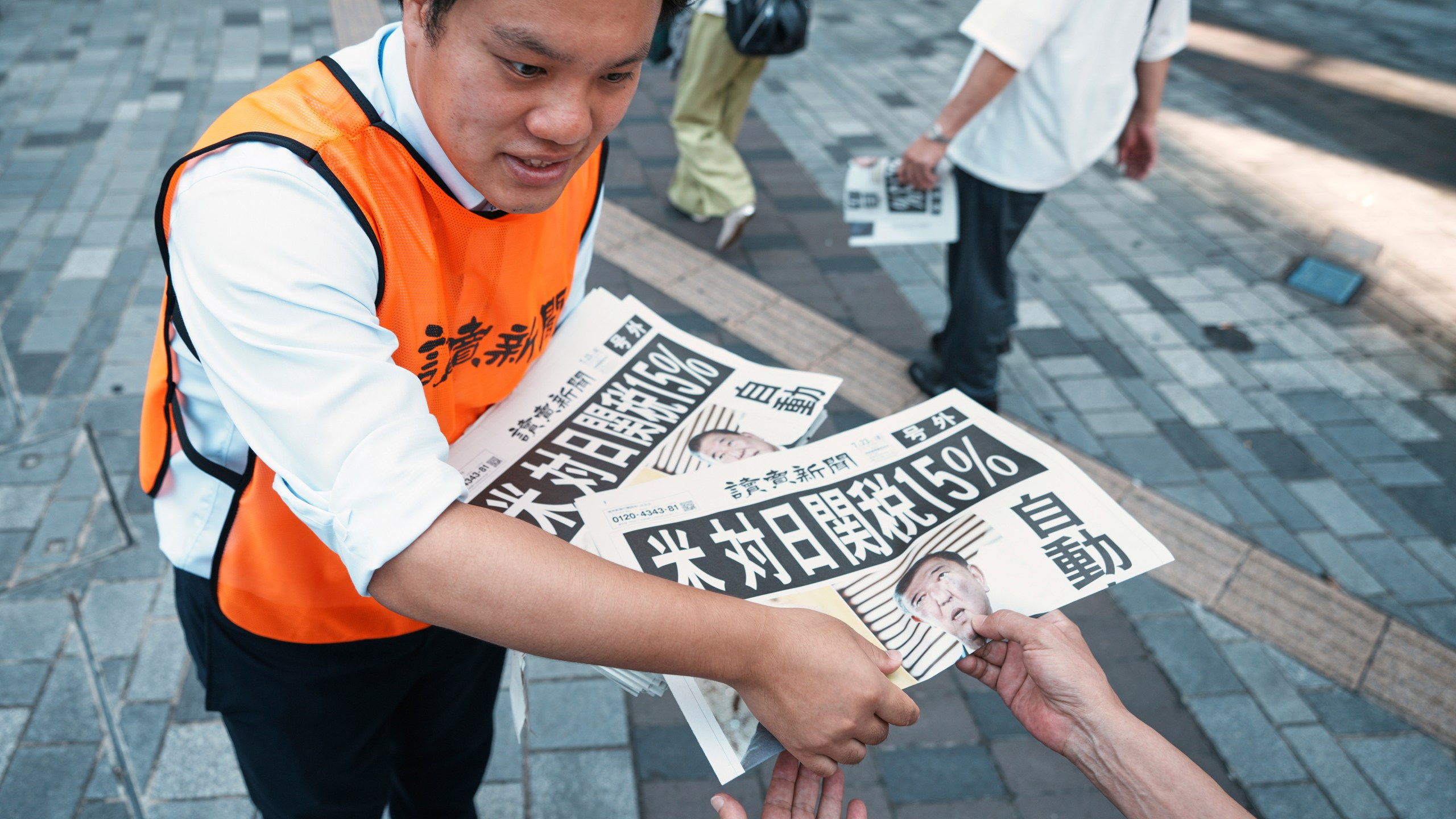 A staff member distributes an extra edition of the Yomiuri Shimbun newspaper reporting that President Donald Trump announced a trade framework with Japan on Tuesday, Wednesday, July 23, 2025, in Tokyo. (AP Photo/Eugene Hoshiko)