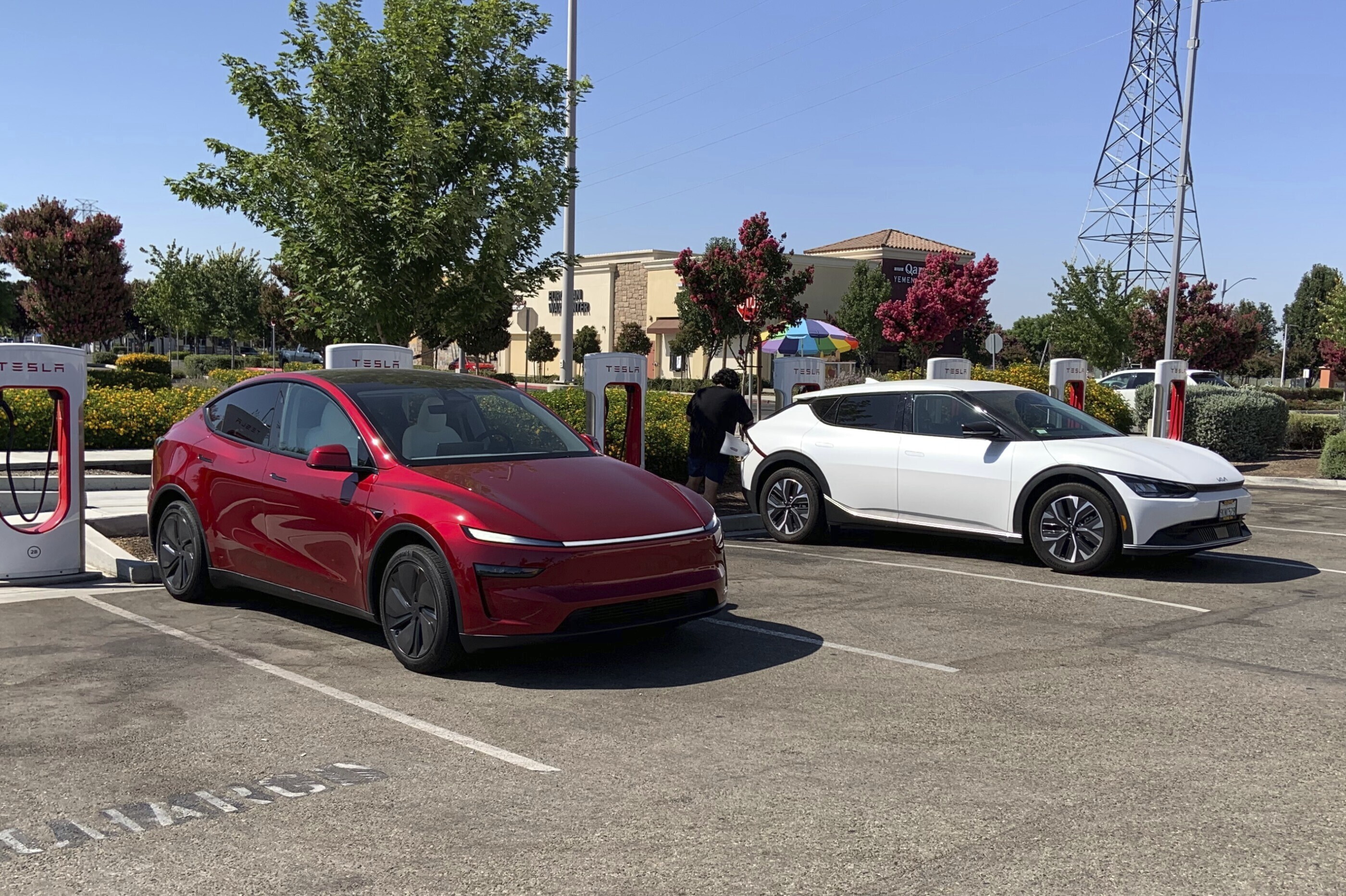 This photo provided by Edmunds shows a Tesla Model Y and a Kia EV6 parked at a Tesla Supercharger station in Fresno, Calif. Planning a cross-country trip in an EV takes extra effort, but doing it properly can make the journey almost as smooth as in a gas-powered vehicle. (Courtesy of Edmunds via AP)