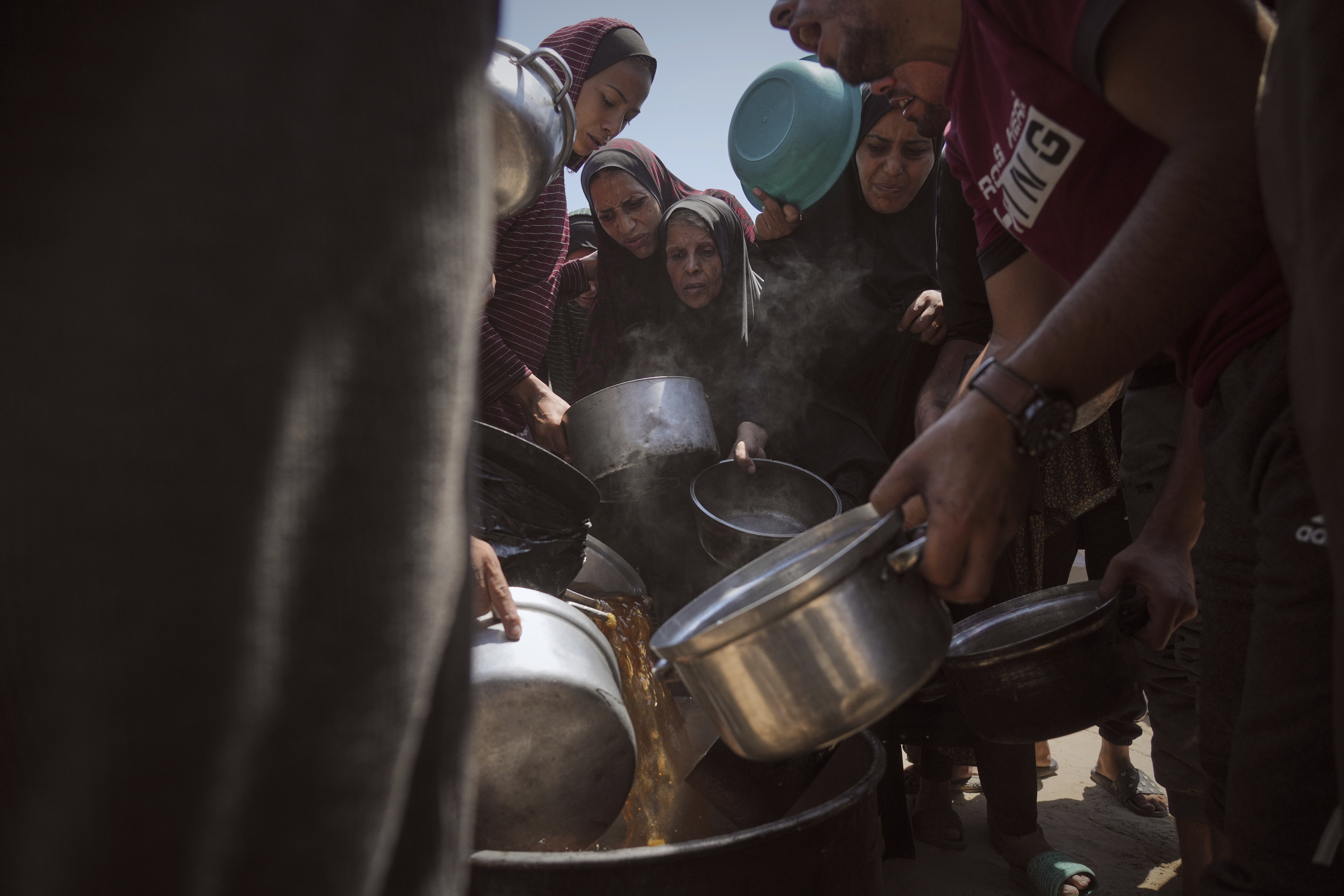 Displaced Palestinians receive donated food at a community kitchen in Gaza City, northern Gaza Strip, Tuesday, July 22, 2025. (AP Photo/Jehad Alshrafi)