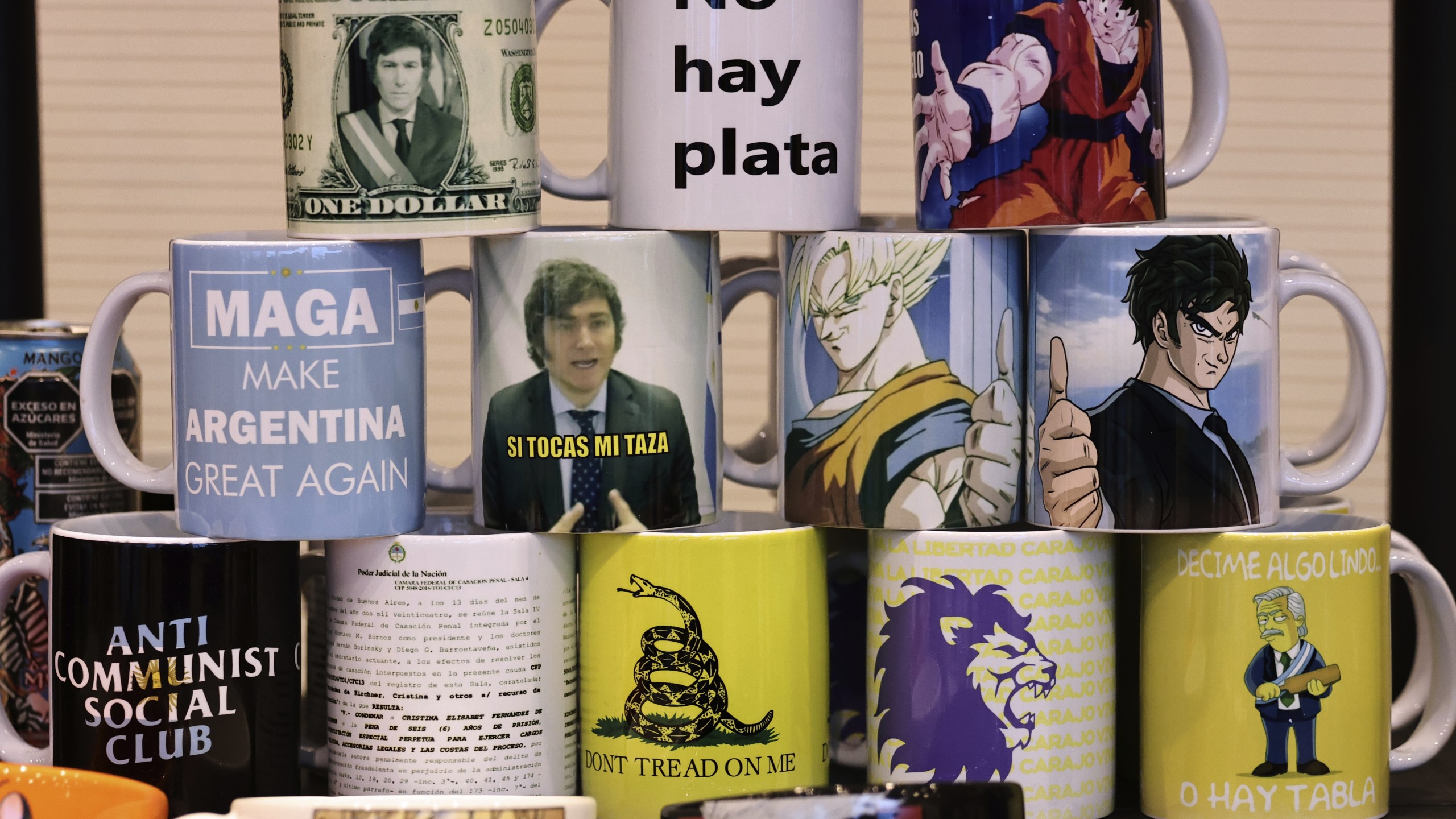 Mugs sit for sale at an event with President Javier Milei and supporters in Cordoba, Argentina, Tuesday, July 22, 2025. (AP Photo/Nicolas Aguilera)