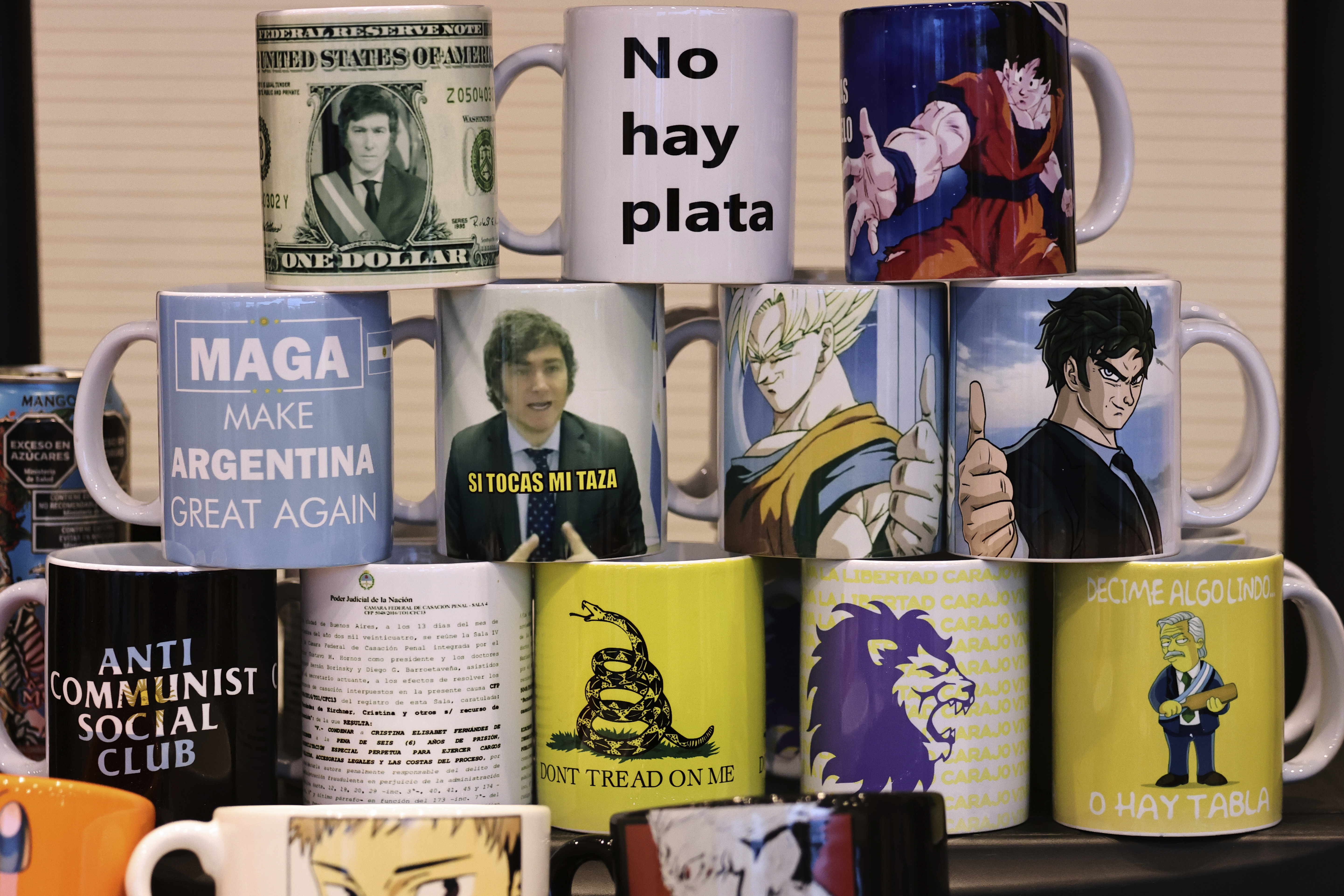 Mugs sit for sale at an event with President Javier Milei and supporters in Cordoba, Argentina, Tuesday, July 22, 2025. (AP Photo/Nicolas Aguilera)