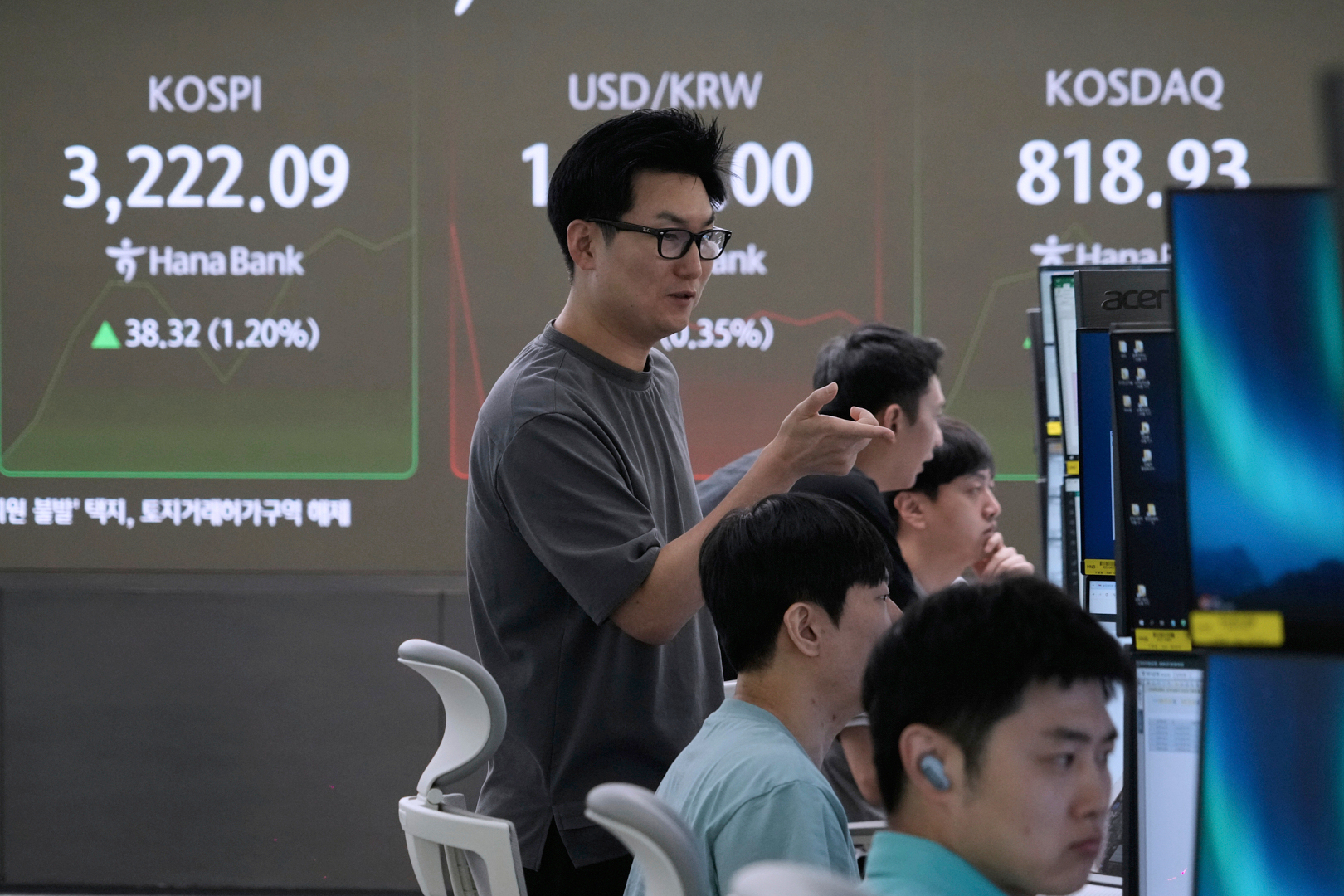Currency traders watch monitors near a screen showing the Korea Composite Stock Price Index (KOSPI), left, at the foreign exchange dealing room of the Hana Bank headquarters in Seoul, South Korea, Thursday, July 24, 2025. (AP Photo/Ahn Young-joon)