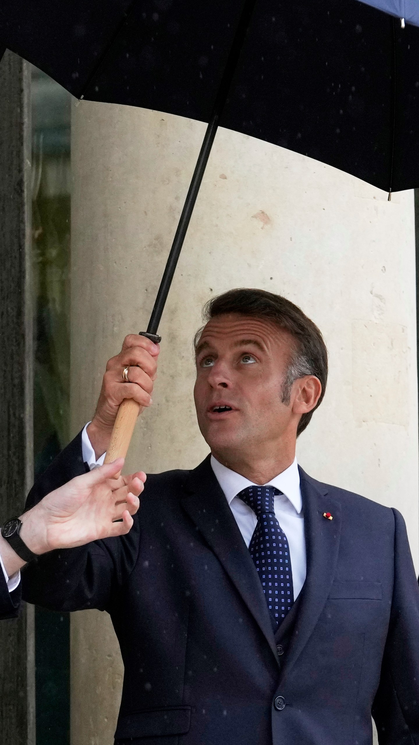 French President Emmanuel Macron uses an umbrella as he waits for Lebanese Prime Minister Nawaf Salam Thursday, July 24, 2025 at the Elysee Palace in Paris. (AP Photo/Michel Euler)