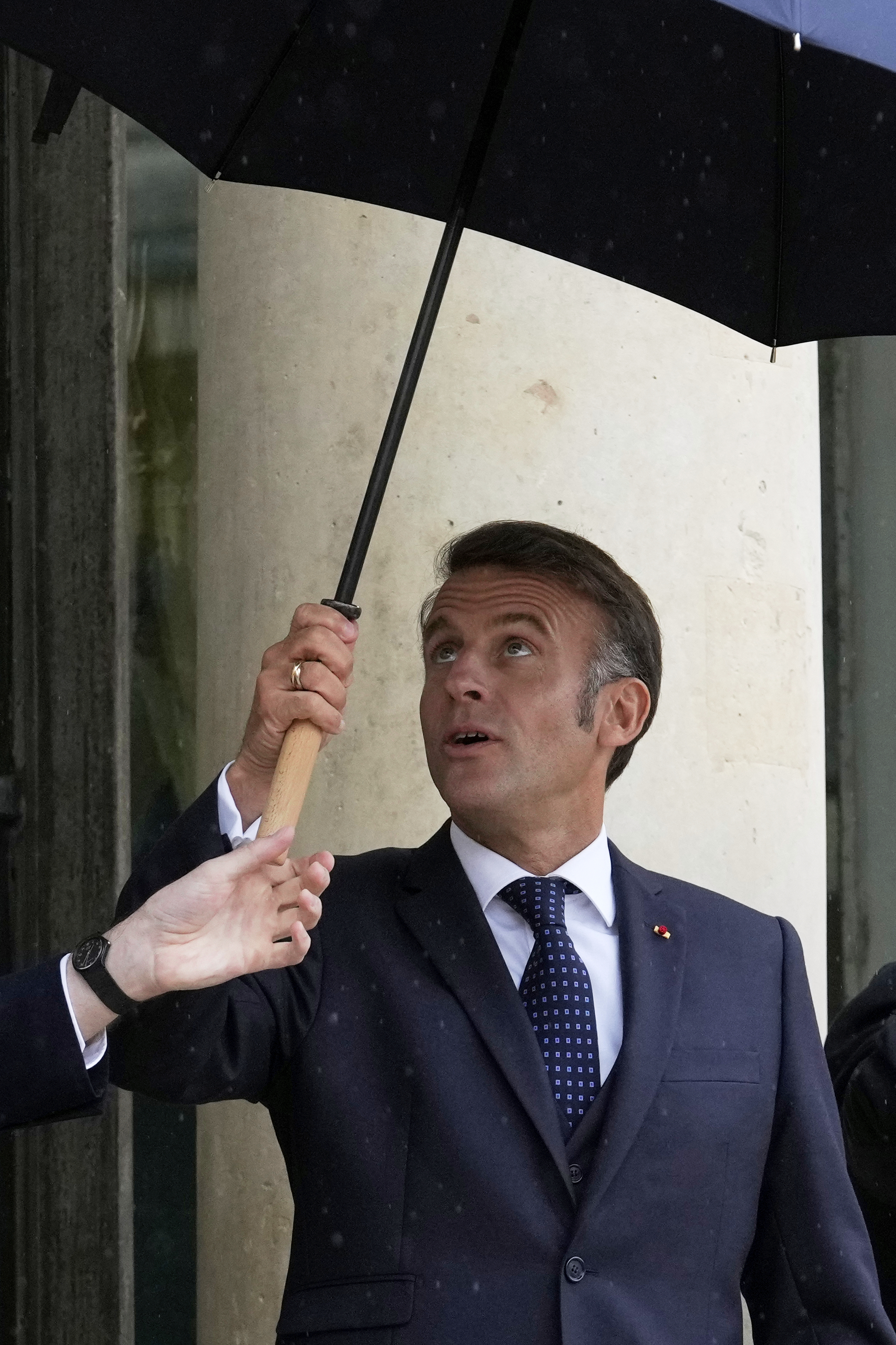 French President Emmanuel Macron uses an umbrella as he waits for Lebanese Prime Minister Nawaf Salam Thursday, July 24, 2025 at the Elysee Palace in Paris. (AP Photo/Michel Euler)