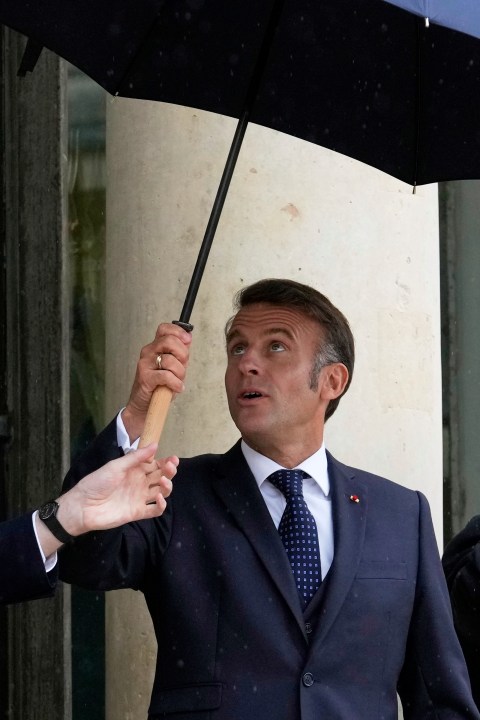 French President Emmanuel Macron uses an umbrella as he waits for Lebanese Prime Minister Nawaf Salam Thursday, July 24, 2025 at the Elysee Palace in Paris. (AP Photo/Michel Euler)