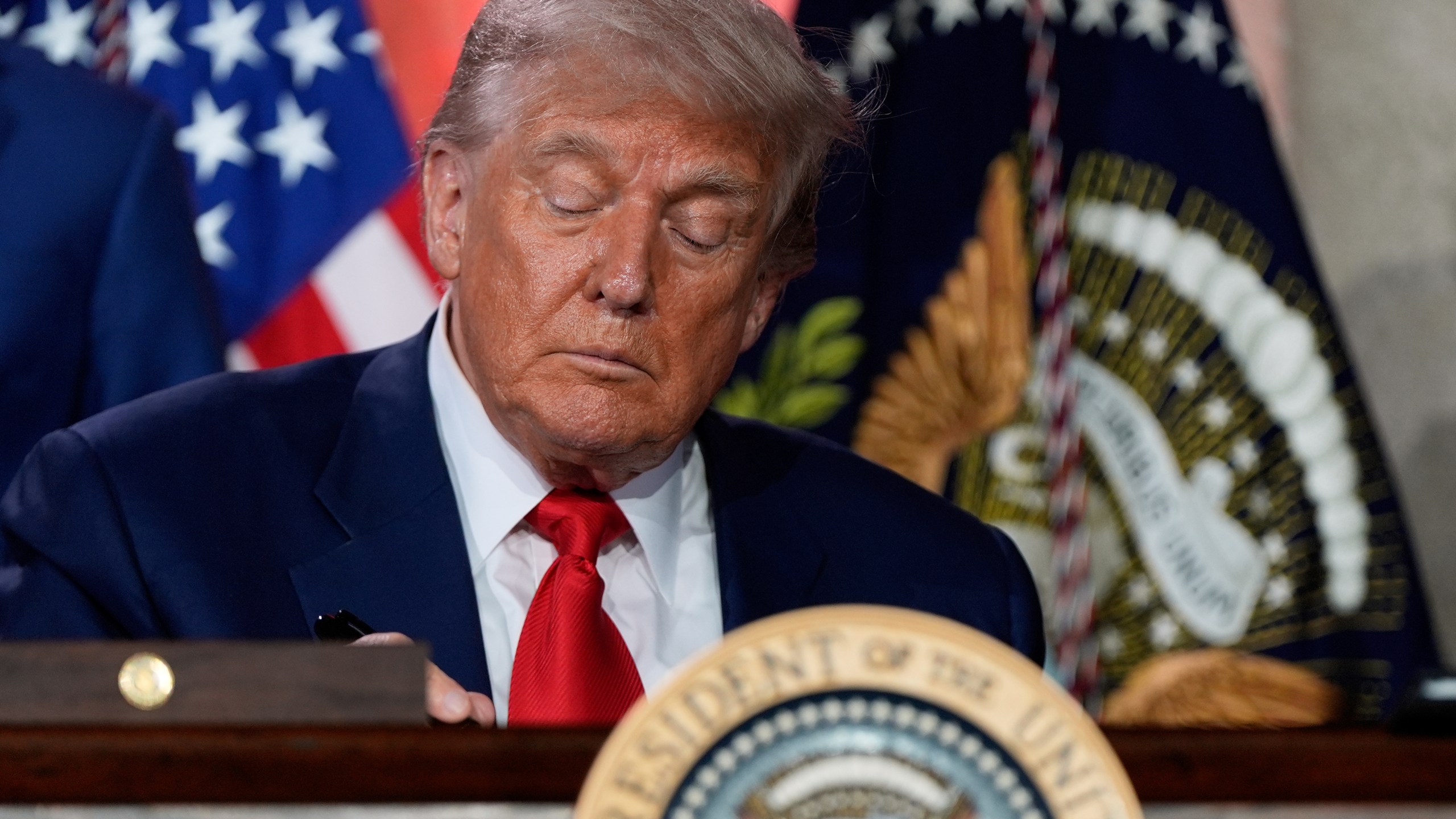President Donald Trump signs executive orders after speaking during an AI summit at the Andrew W. Mellon Auditorium, Wednesday, July 23, 2025, in Washington. (AP Photo/Julia Demaree Nikhinson)