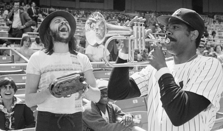 FILE - New York Yankees Pitcher Dock Ellis, right, has a little fun with a Chuck Mangione's horn before a game with the Toronto Blue Jays at Yankee Stadium, April 19, 1977, in New York. (AP Photo/Ray Stubblebine, file)