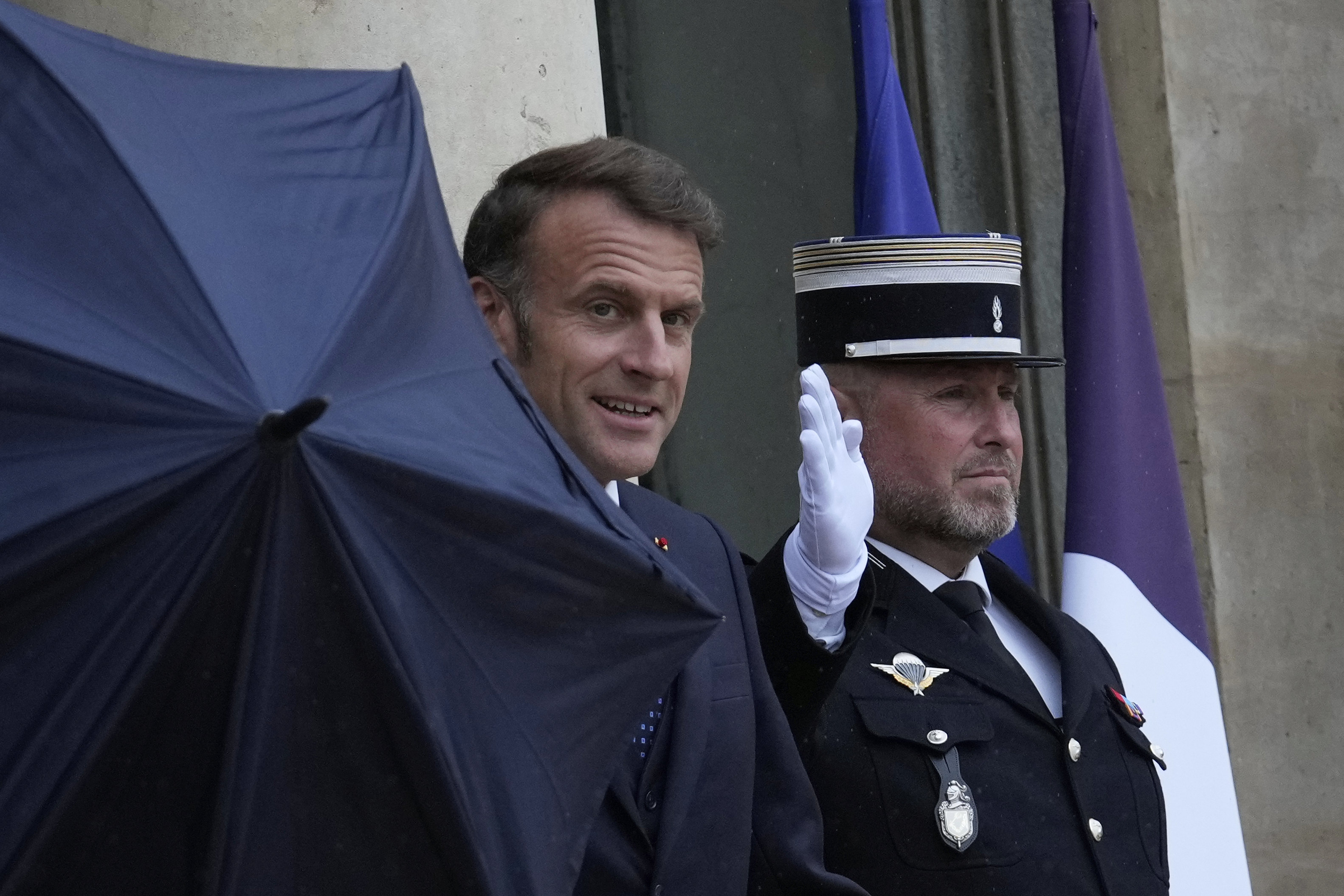 French President Emmanuel Macron uses an umbrella as he waits for Lebanese Prime Minister Nawaf Salam Thursday, July 24, 2025 at the Elysee Palace in Paris. (AP Photo/Michel Euler)