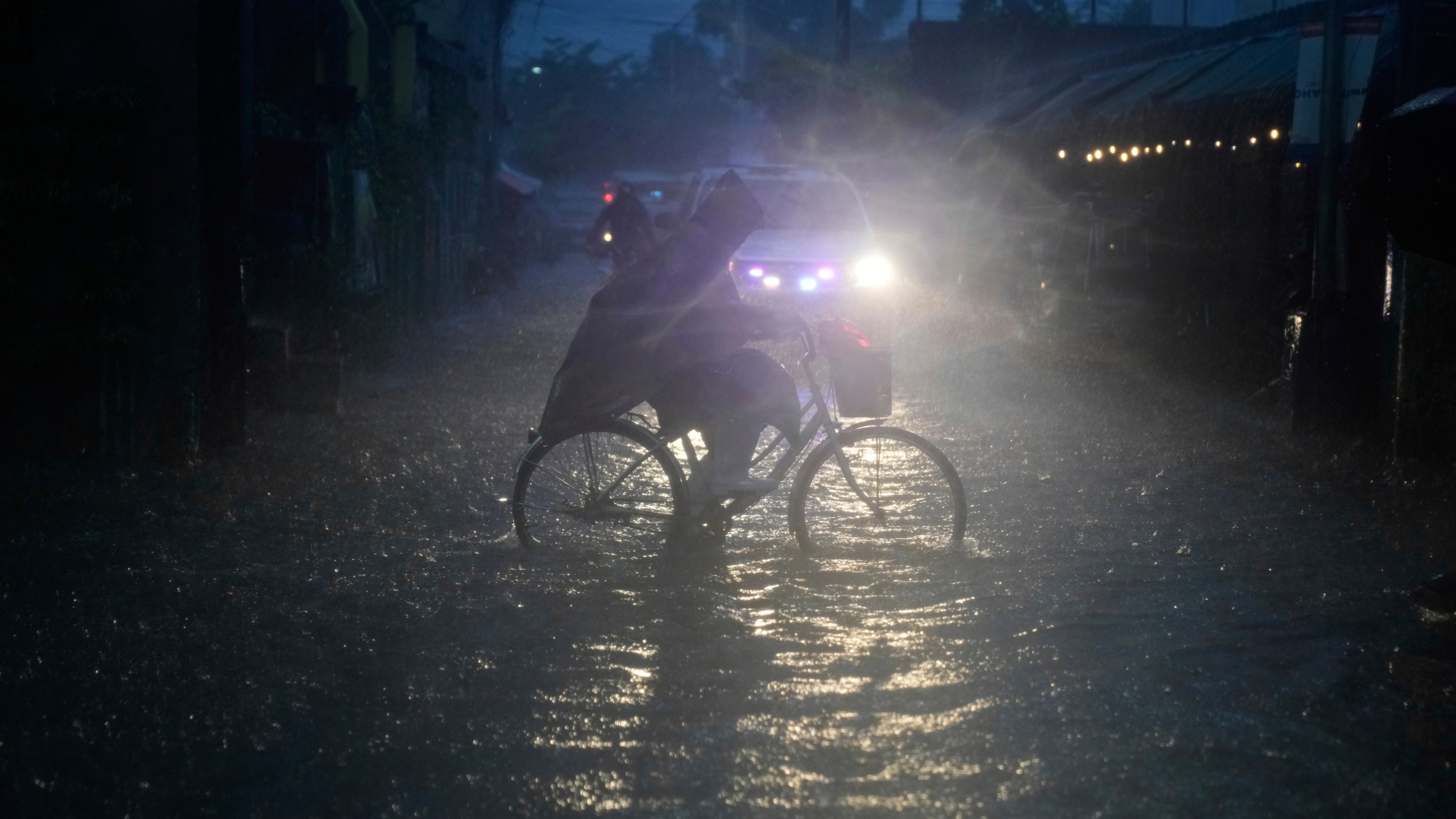 A man pedals his bicycle along a flooded road as intense rains continue due to the southwest monsoon at Malabon city, Philippines on Thursday, July 24, 2025. (AP Photo/Aaron Favila)