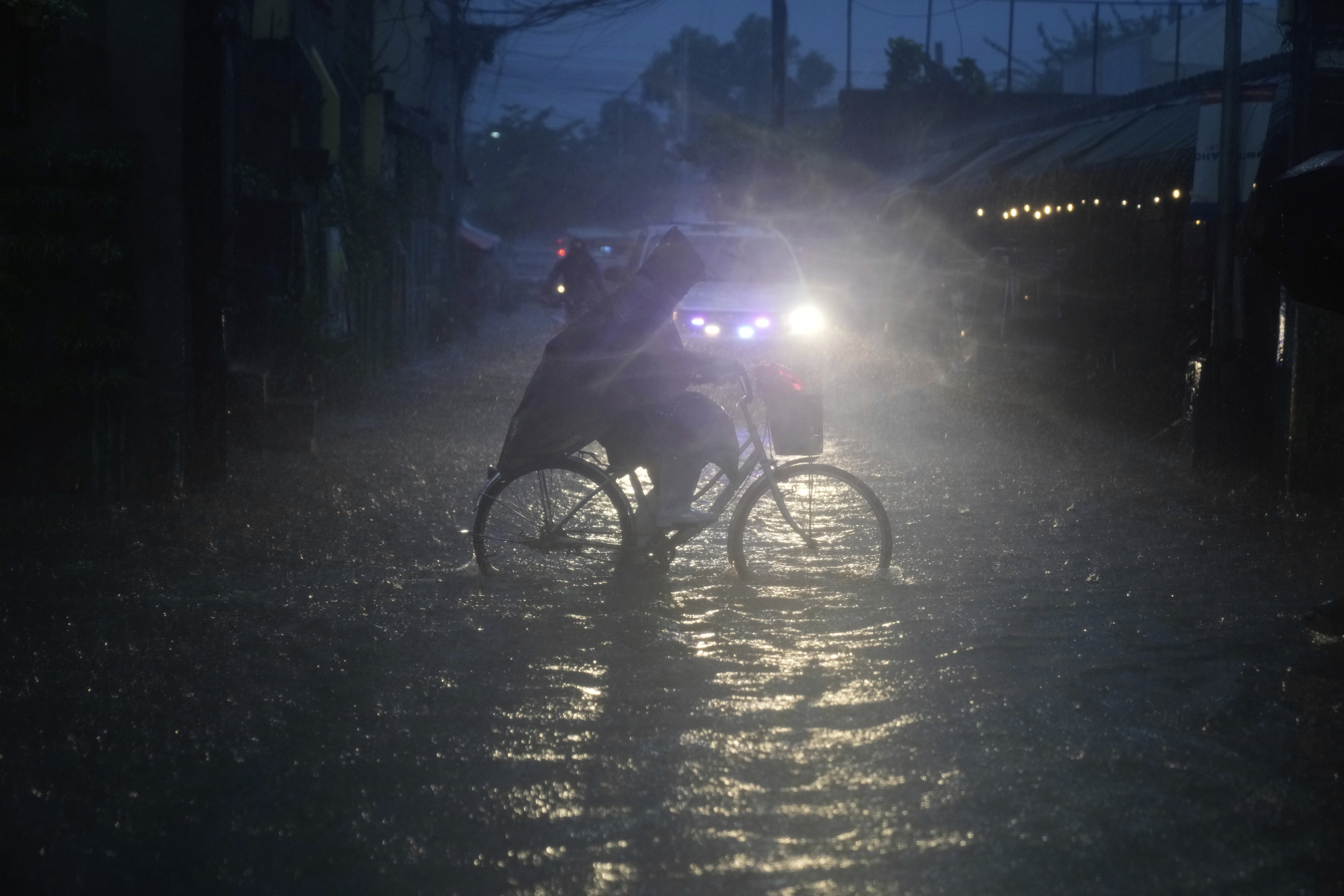 A man pedals his bicycle along a flooded road as intense rains continue due to the southwest monsoon at Malabon city, Philippines on Thursday, July 24, 2025. (AP Photo/Aaron Favila)