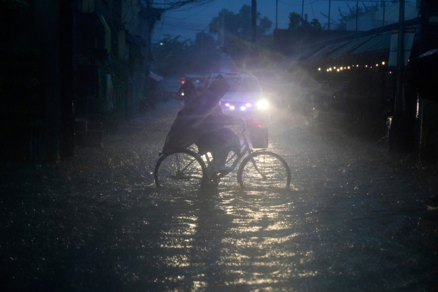A man pedals his bicycle along a flooded road as intense rains continue due to the southwest monsoon at Malabon city, Philippines on Thursday, July 24, 2025. (AP Photo/Aaron Favila)