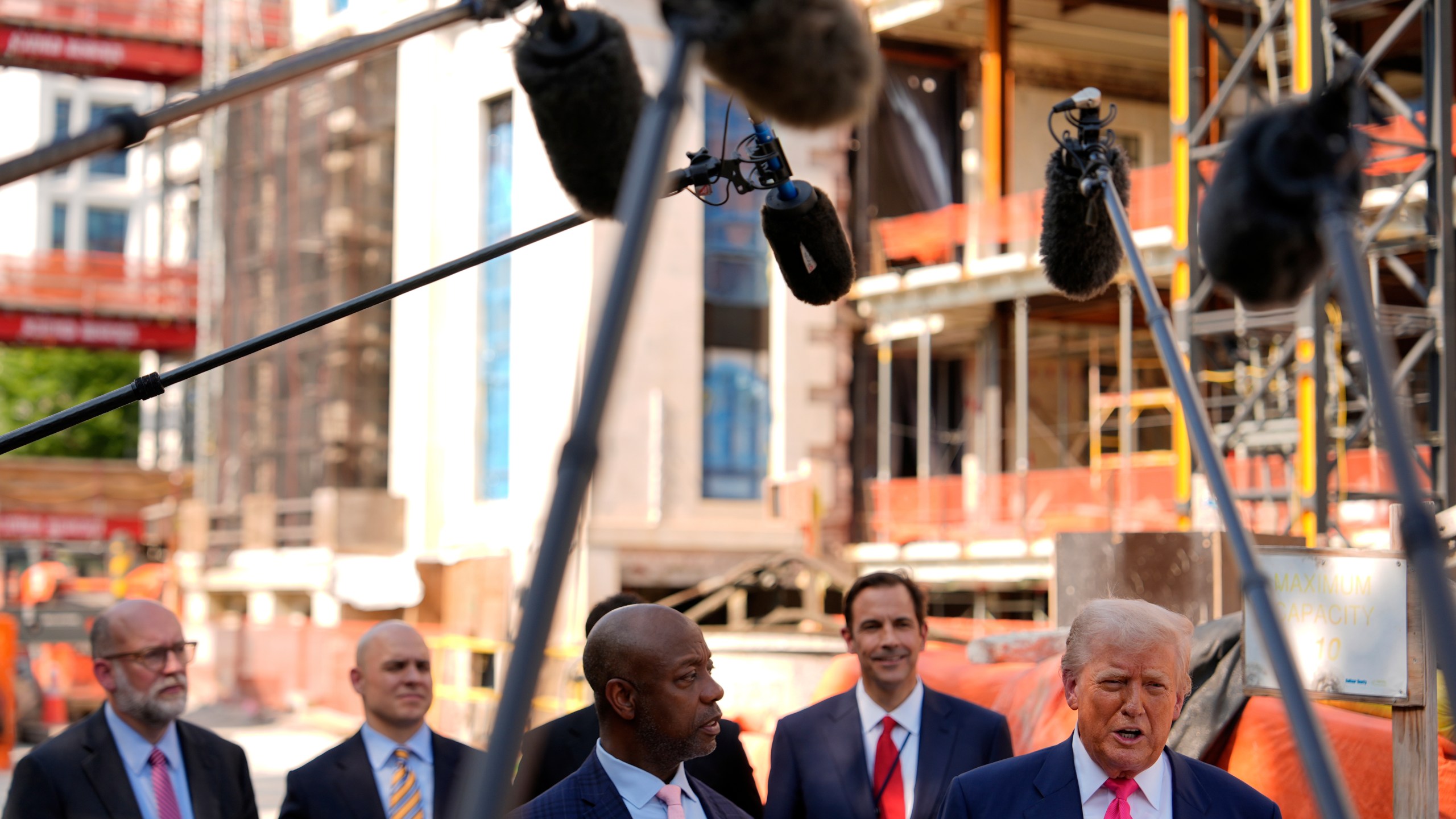 President Donald Trump speaks as Sen. Tim Scott, R-S.C., in foreground left, and from background left, Russell Vought, director of the Office of Management and Budget, White House Deputy Chief of Staff James Blair and Mark Paoletta, general counsel with the Office of Management and Budget, listen as Trump visits the Federal Reserve, Thursday, July 24, 2025, in Washington. (AP Photo/Julia Demaree Nikhinson)