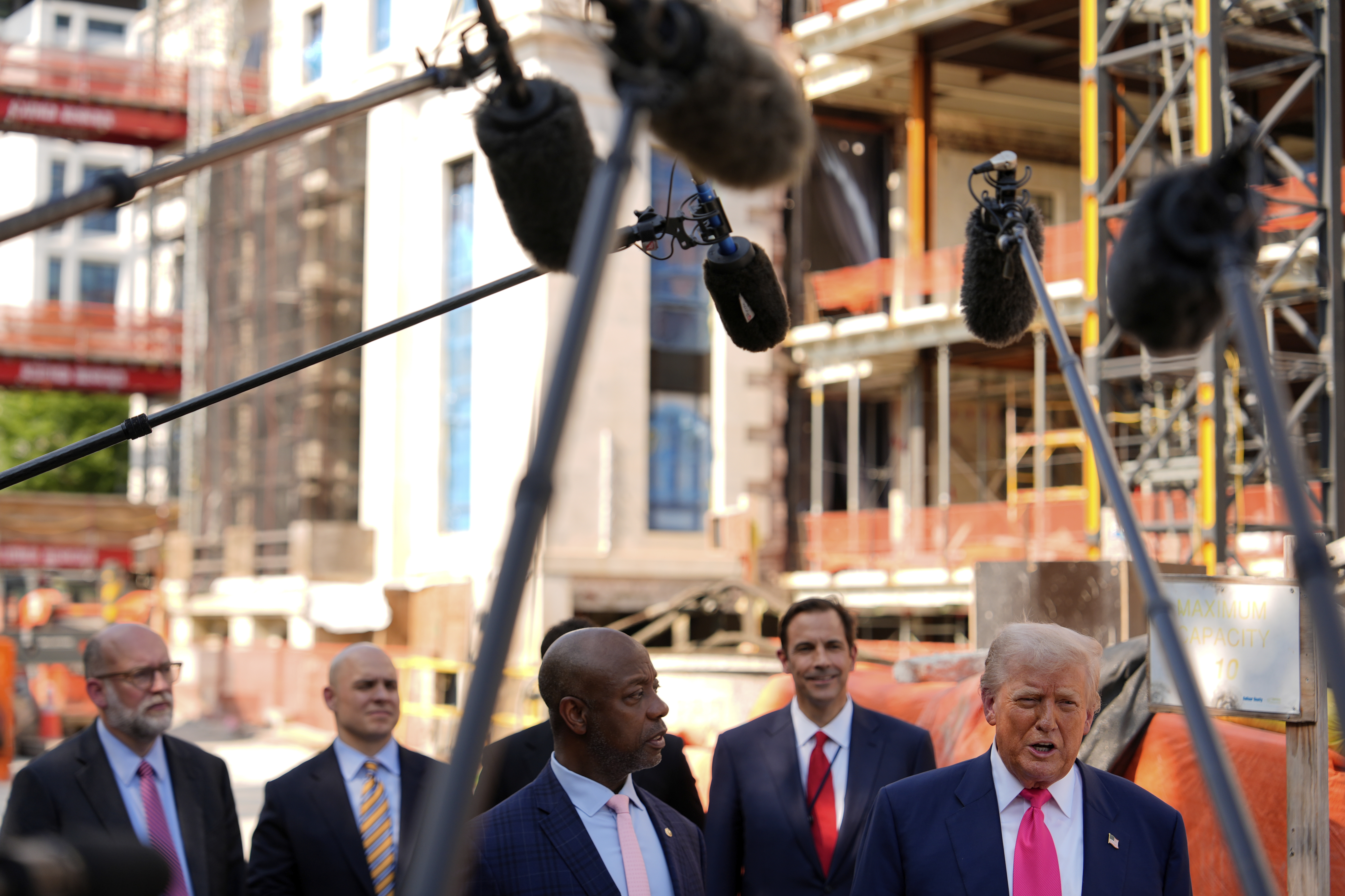 President Donald Trump speaks as Sen. Tim Scott, R-S.C., in foreground left, and from background left, Russell Vought, director of the Office of Management and Budget, White House Deputy Chief of Staff James Blair and Mark Paoletta, general counsel with the Office of Management and Budget, listen as Trump visits the Federal Reserve, Thursday, July 24, 2025, in Washington. (AP Photo/Julia Demaree Nikhinson)
