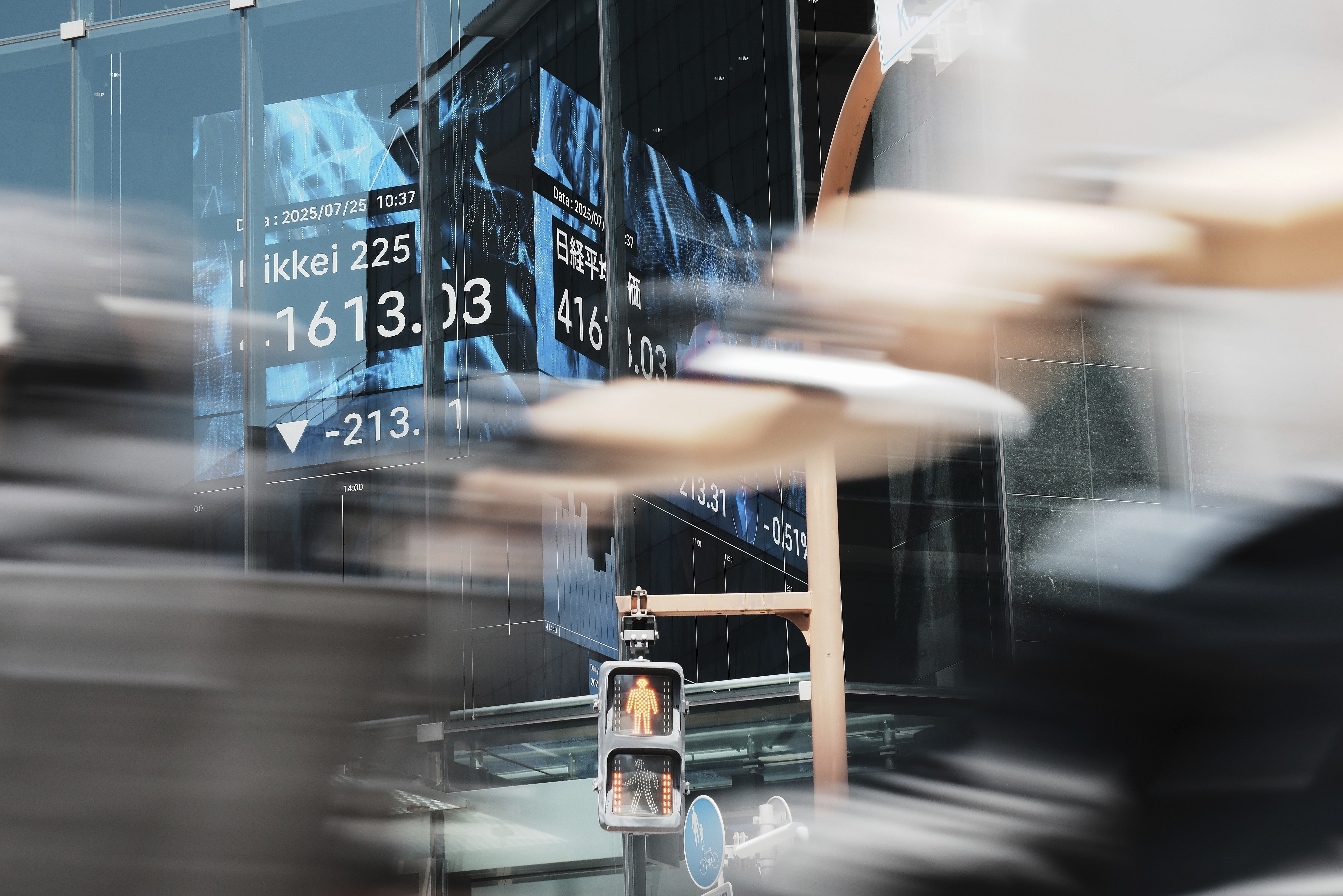 A person rides a bicycle past an electronic stock board showing Japan's Nikkei index at a securities firm Friday, July 25, 2025, in Tokyo. (AP Photo/Eugene Hoshiko)