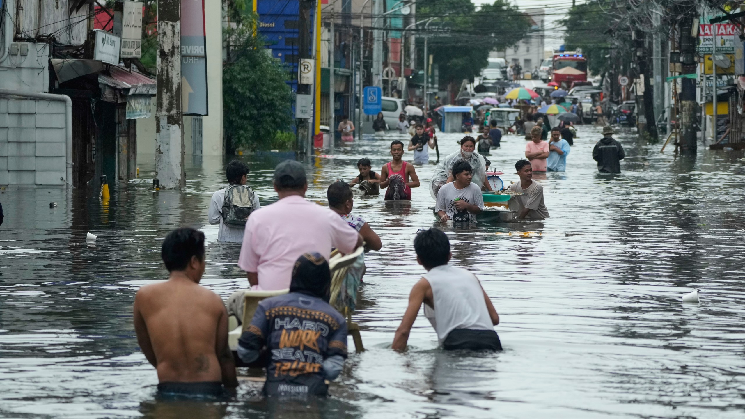 Residents wade along a flooded road as Typhoon Co-may intensified seasonal monsoon rains at Malabon city, Philippines on Friday, July 25, 2025. (AP Photo/Aaron Favila)