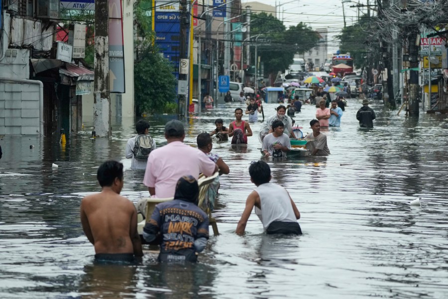 Residents wade along a flooded road as Typhoon Co-may intensified seasonal monsoon rains at Malabon city, Philippines on Friday, July 25, 2025. (AP Photo/Aaron Favila)