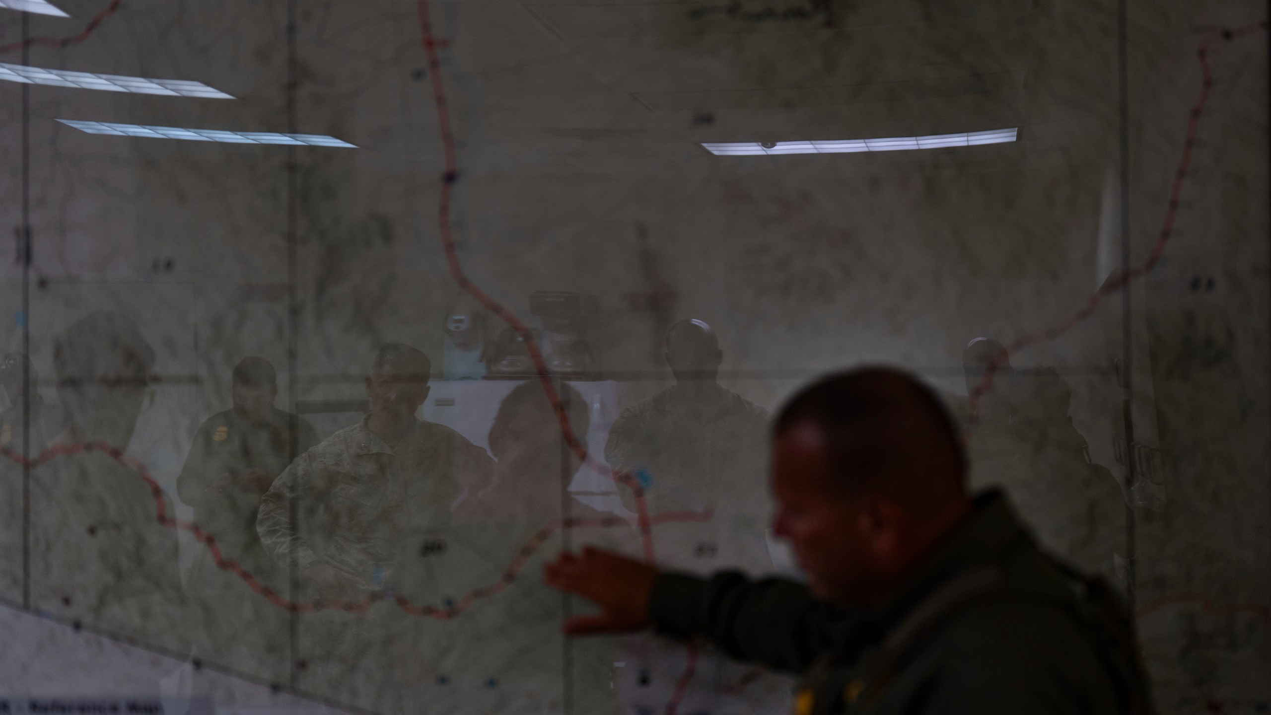 U.S. military personnel are reflected on a map as they listen to Jose Luis Maheda during a briefing at the U.S. Border Patrol station in Nogales, Ariz., Tuesday, July 22, 2025. (AP Photo/Jae C. Hong)