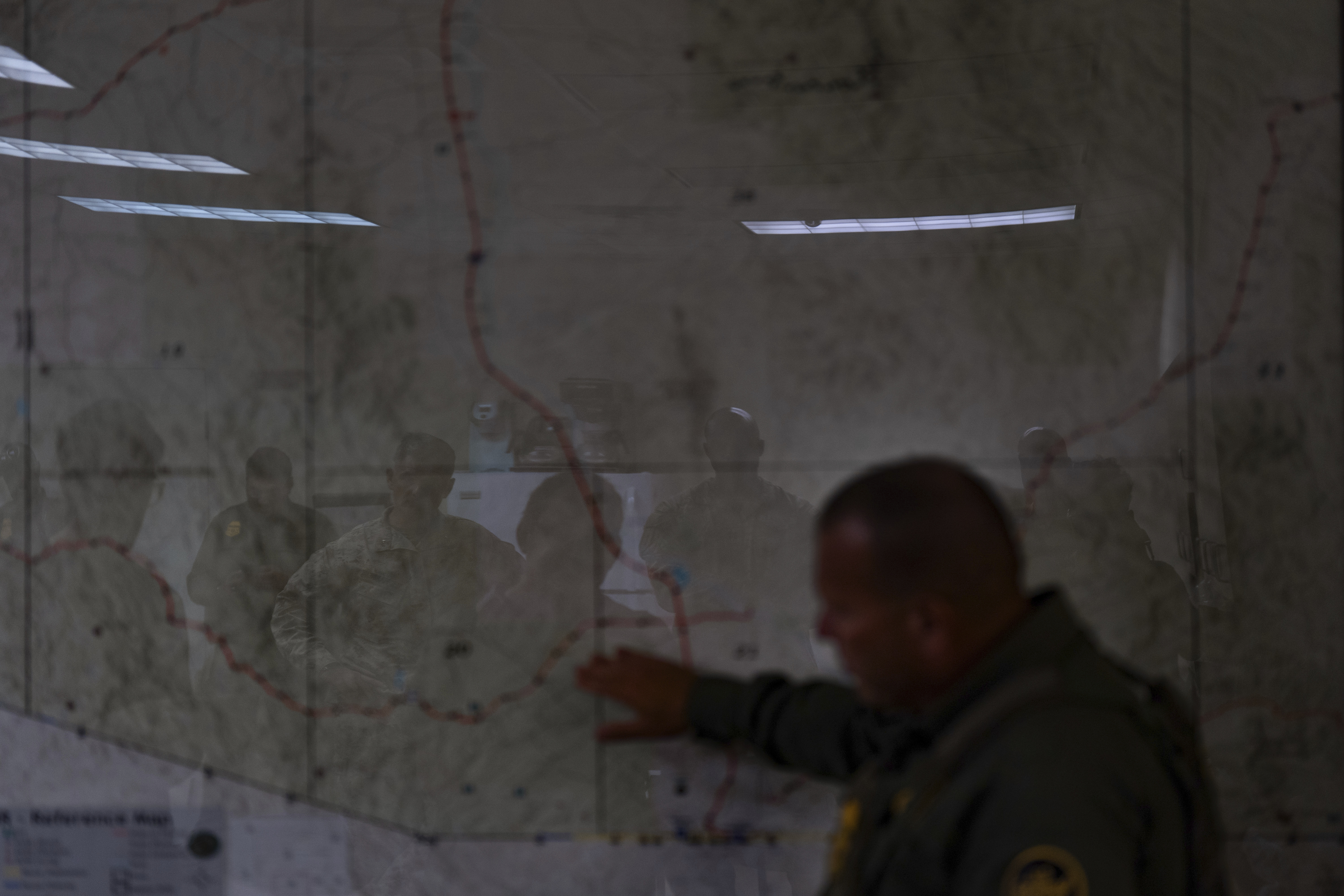 U.S. military personnel are reflected on a map as they listen to Jose Luis Maheda during a briefing at the U.S. Border Patrol station in Nogales, Ariz., Tuesday, July 22, 2025. (AP Photo/Jae C. Hong)