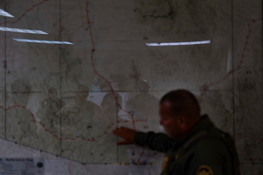 U.S. military personnel are reflected on a map as they listen to Jose Luis Maheda during a briefing at the U.S. Border Patrol station in Nogales, Ariz., Tuesday, July 22, 2025. (AP Photo/Jae C. Hong)
