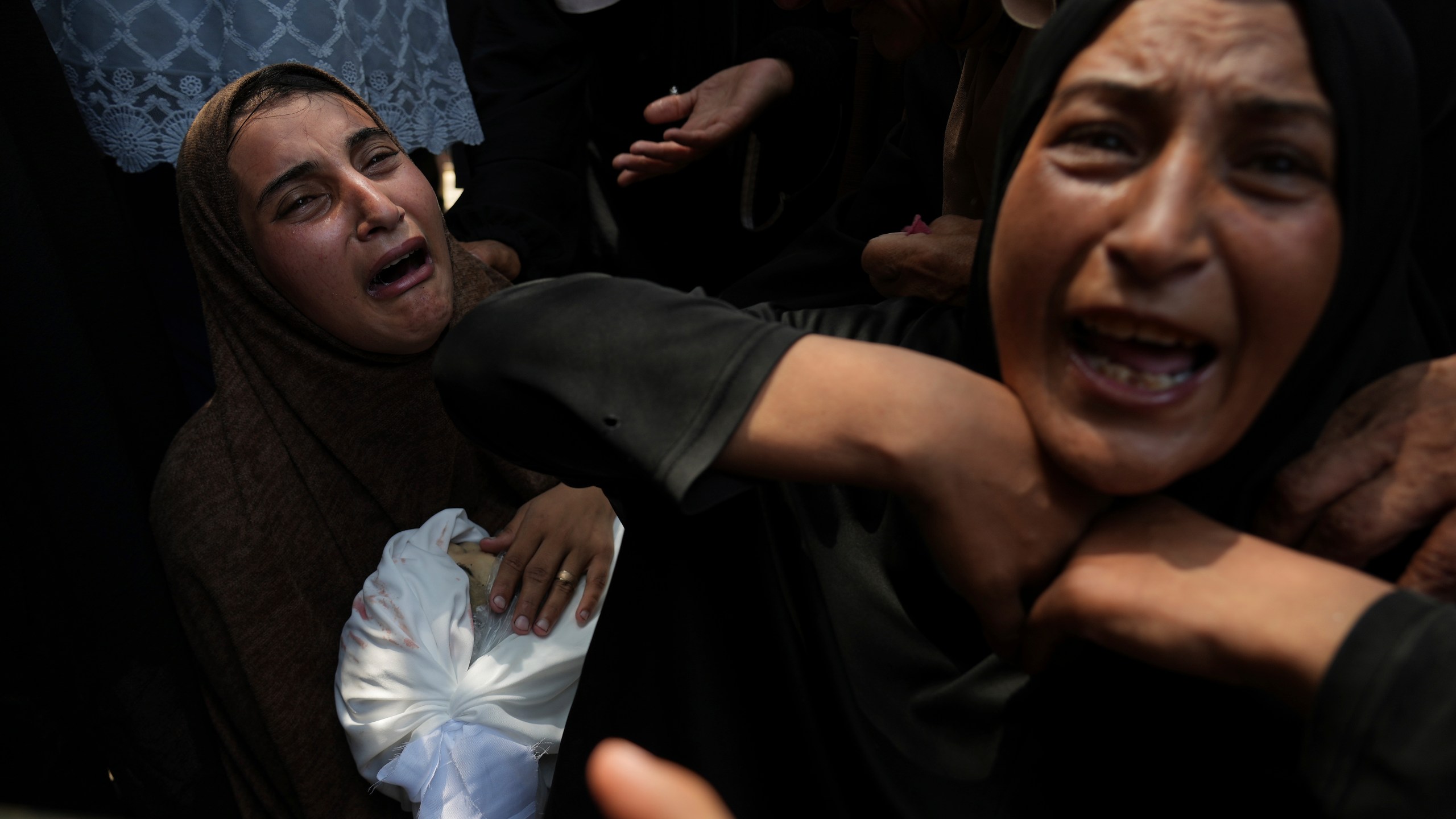 Maysara Adwan, left, mourns as she holds the body of her 11-year-old son, Qais, who was killed in an Israeli airstrike on a school in Gaza that has been used as a shelter, during his burial at Al Shifa Hospital in Gaza City, Friday, July 25, 2025. (AP Photo/Abdel Kareem Hana)