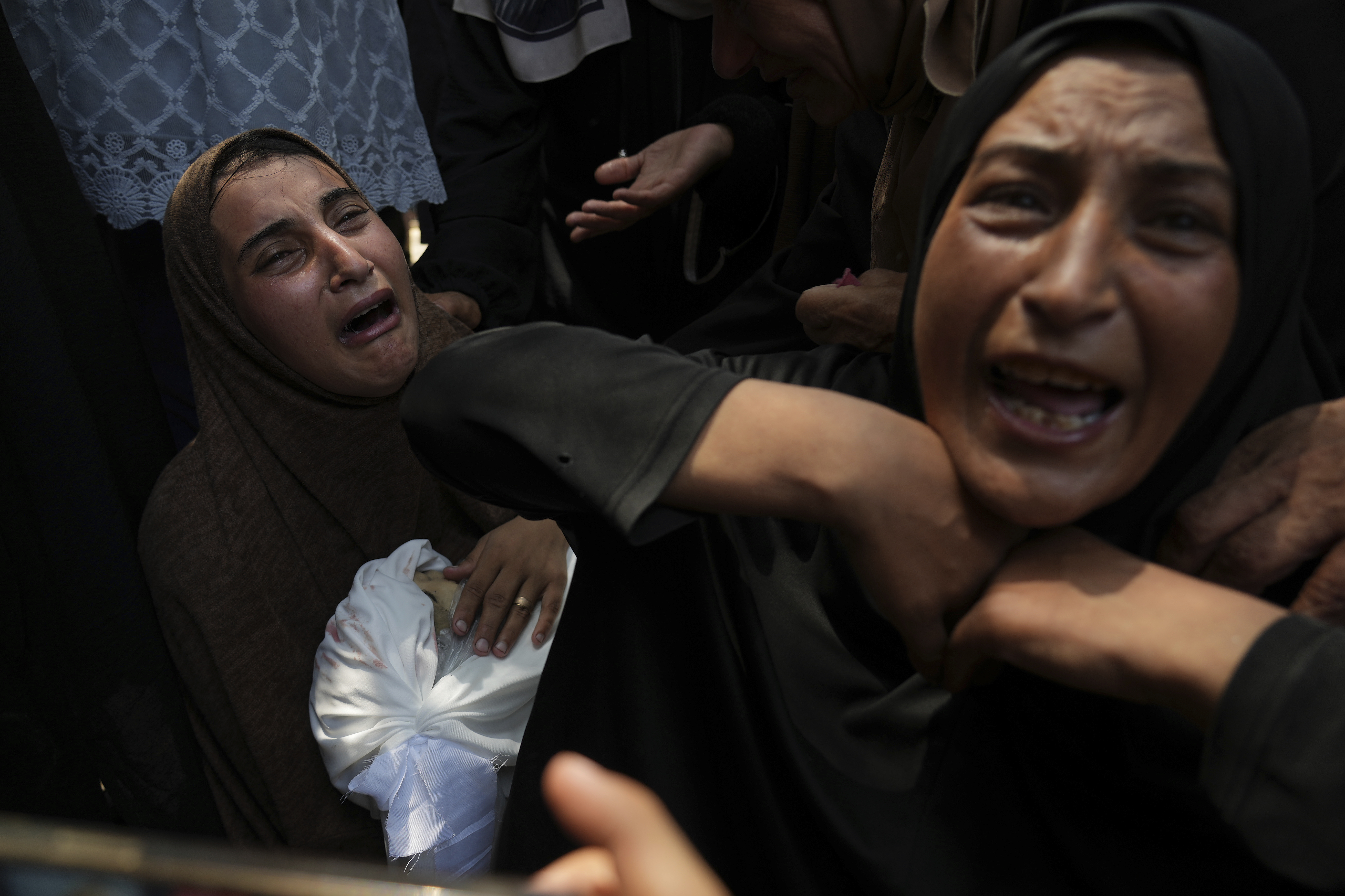 Maysara Adwan, left, mourns as she holds the body of her 11-year-old son, Qais, who was killed in an Israeli airstrike on a school in Gaza that has been used as a shelter, during his burial at Al Shifa Hospital in Gaza City, Friday, July 25, 2025. (AP Photo/Abdel Kareem Hana)