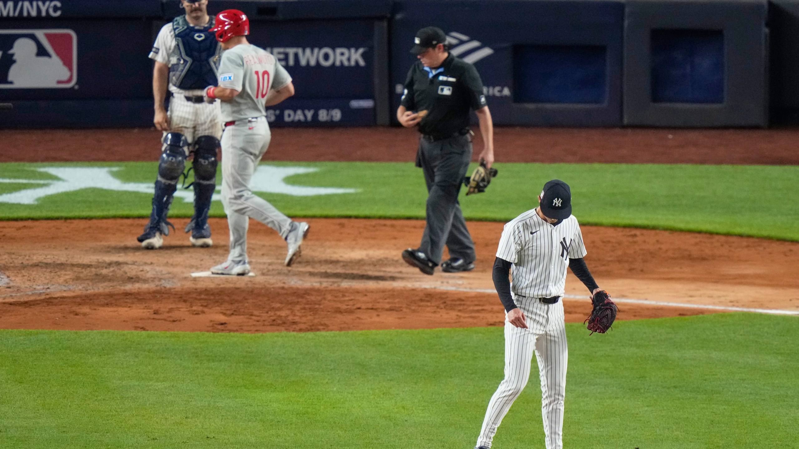 New York Yankees pitcher Luke Weaver, right, looks down as Philadelphia Phillies' J.T. Realmuto reaches home plate after hitting a three-run home run during the seventh inning of a baseball game Friday, July 25, 2025, in New York. (AP Photo/Frank Franklin II)