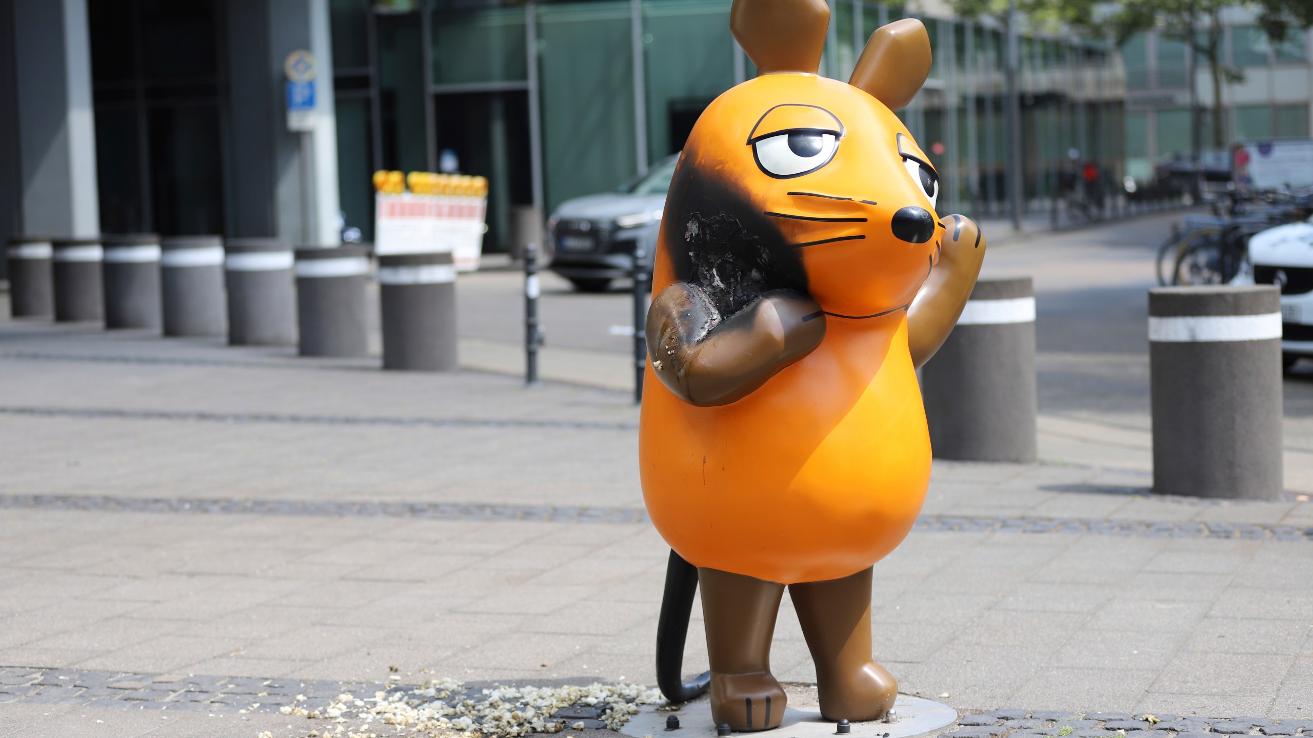 A mouse statue that has been set on fire stands in front of the WDR (West German Broadcasting Corporation) building in Cologne, Germany, Saturday, July 26, 2025. (Sascha Thelen/dpa via AP)