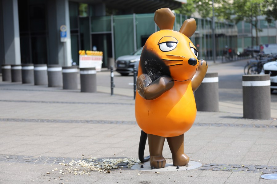 A mouse statue that has been set on fire stands in front of the WDR (West German Broadcasting Corporation) building in Cologne, Germany, Saturday, July 26, 2025. (Sascha Thelen/dpa via AP)