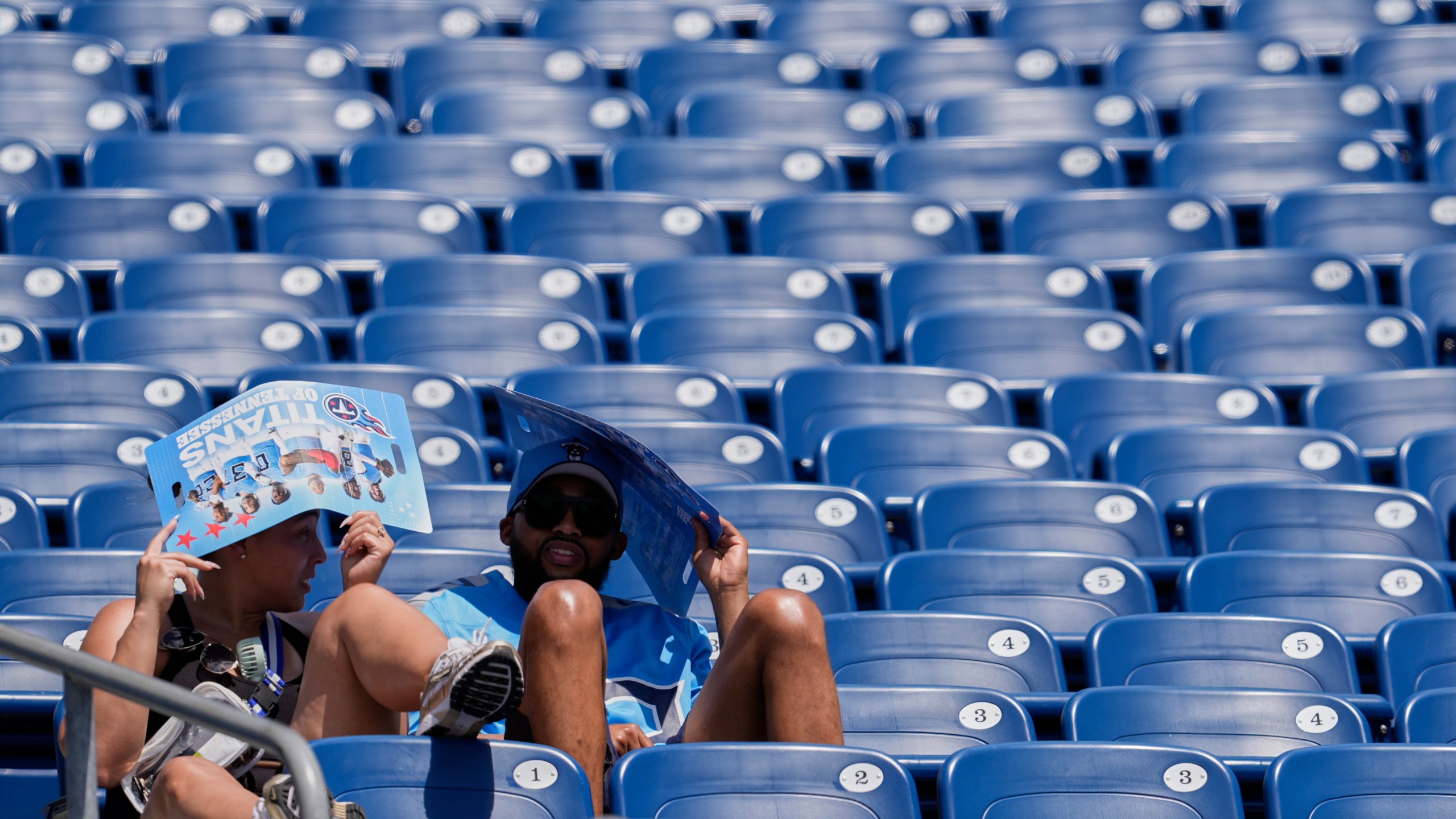 Tennessee Titans fans cover their heads in the heat during "Back Together Weekend" at the team's NFL football training camp Saturday, July 26, 2025, in Nashville, Tenn. (AP Photo/George Walker IV)