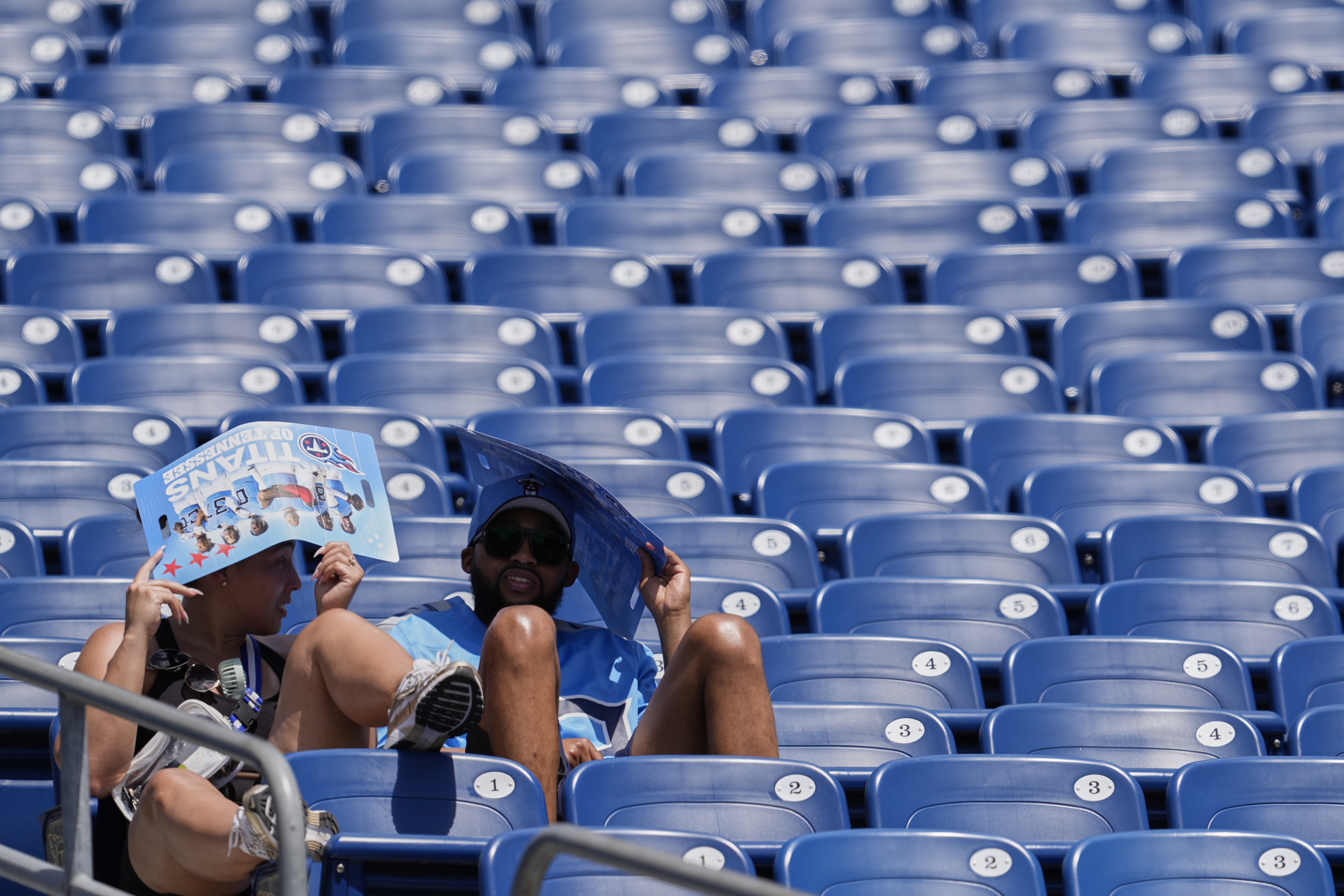 Tennessee Titans fans cover their heads in the heat during "Back Together Weekend" at the team's NFL football training camp Saturday, July 26, 2025, in Nashville, Tenn. (AP Photo/George Walker IV)