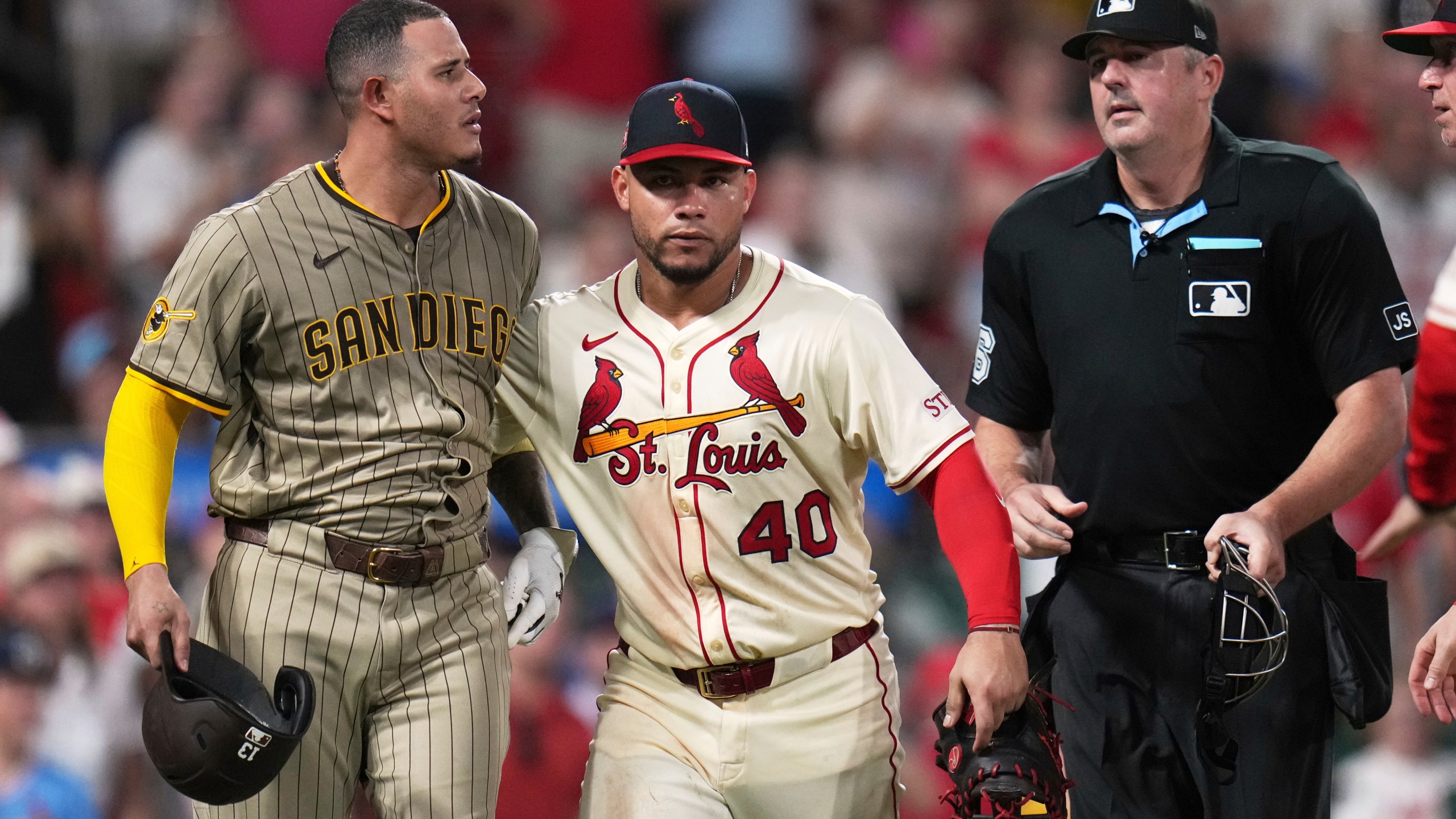 San Diego Padres' Manny Machado, left, is held back by St. Louis Cardinals' Willson Contreras (40) after being hit by a pitch as home plate umpire Lance Barrett, right, watches during the ninth inning of a baseball game against the St. Louis Cardinals Saturday, July 26, 2025, in St. Louis. (AP Photo/Jeff Roberson)
