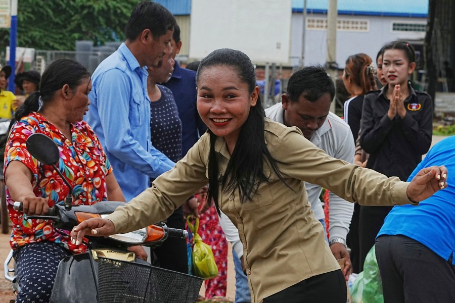 A Cambodian youth volunteer Chhar Sin, foreground, greats villagers who donate their personal belongings for the displacing people at a sidewalk in Srey Snam district in Siem Reap province, Cambodia, Saturday, July 26, 2025, during fighting between Thailand and Cambodia. (AP Photo/Heng Sinith)