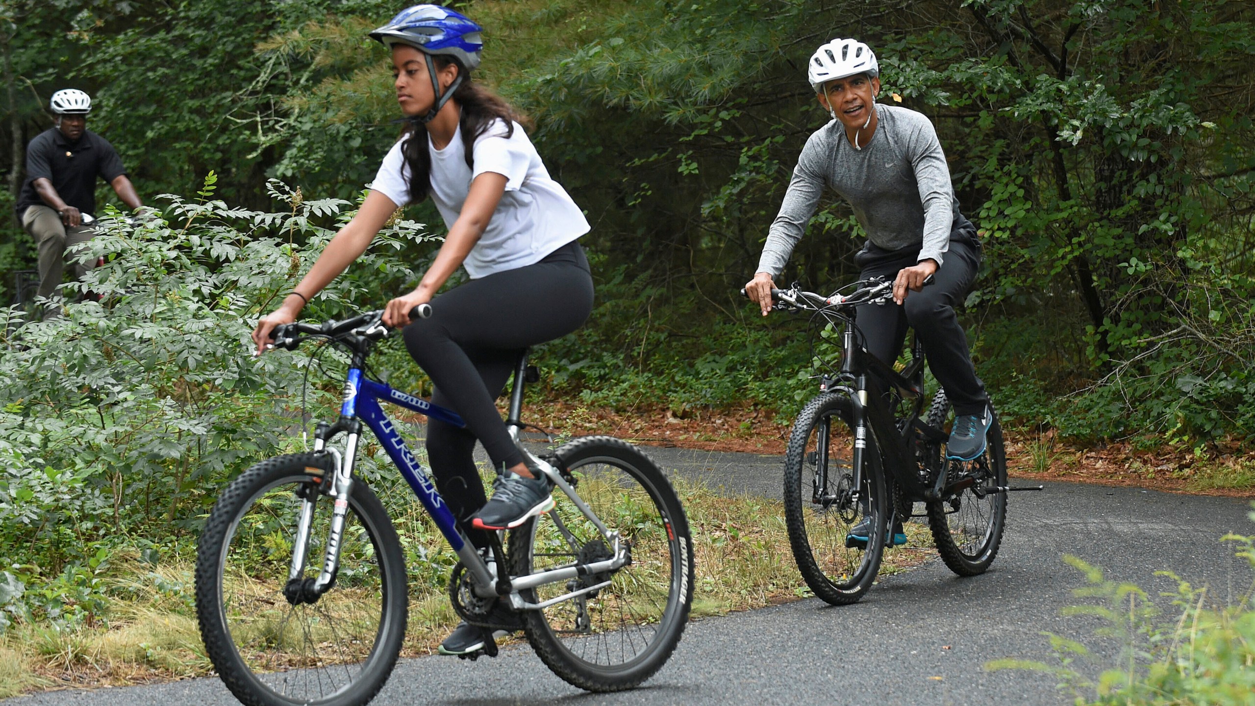 FILE - President Barack Obama follows his daughter Malia Obama as they rides bikes in West Tisbury, Mass., on Martha's Vineyard, Aug. 22, 2015, during the Obamas annual vacation. (AP Photo/Susan Walsh, File)