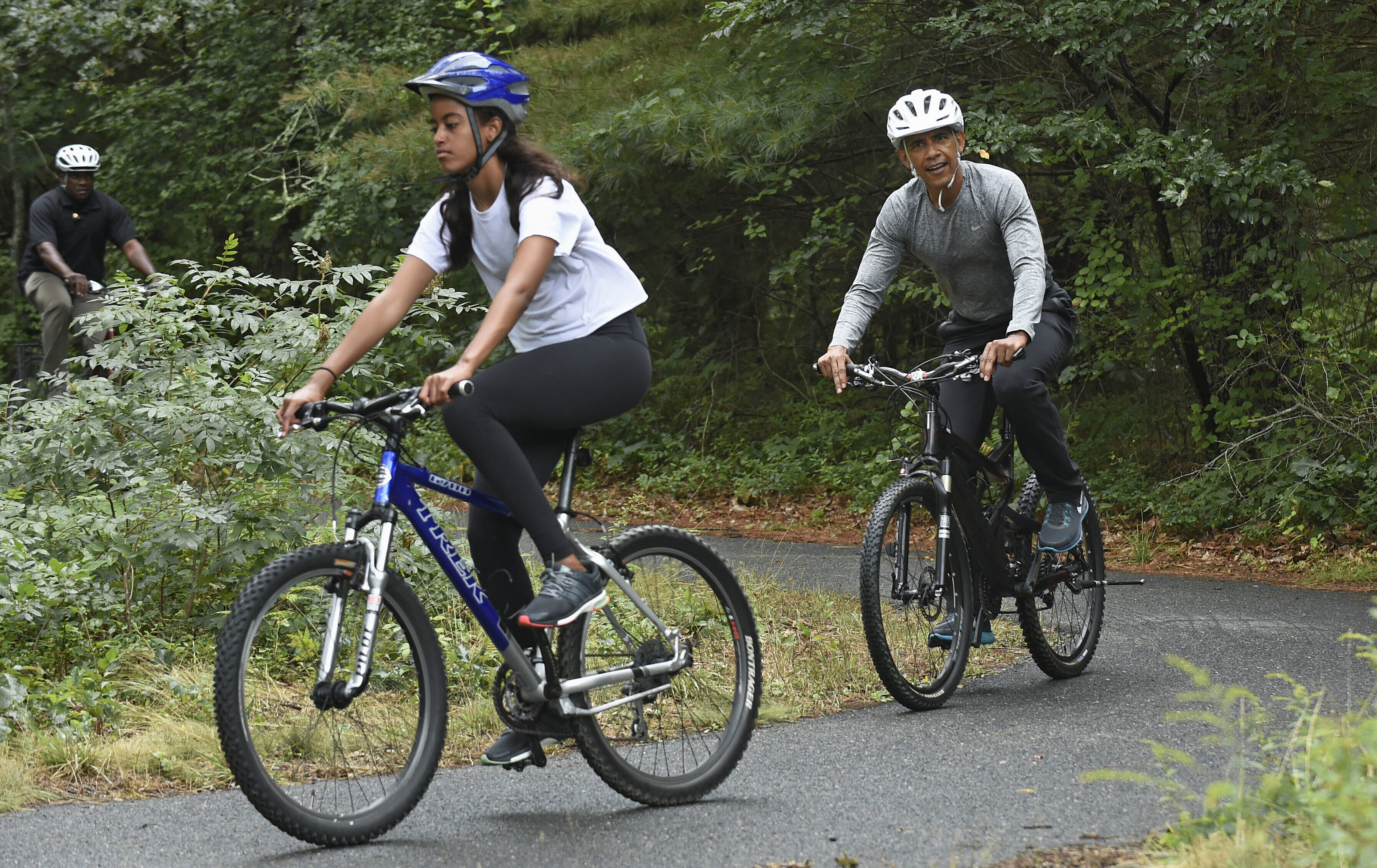 FILE - President Barack Obama follows his daughter Malia Obama as they rides bikes in West Tisbury, Mass., on Martha's Vineyard, Aug. 22, 2015, during the Obamas annual vacation. (AP Photo/Susan Walsh, File)