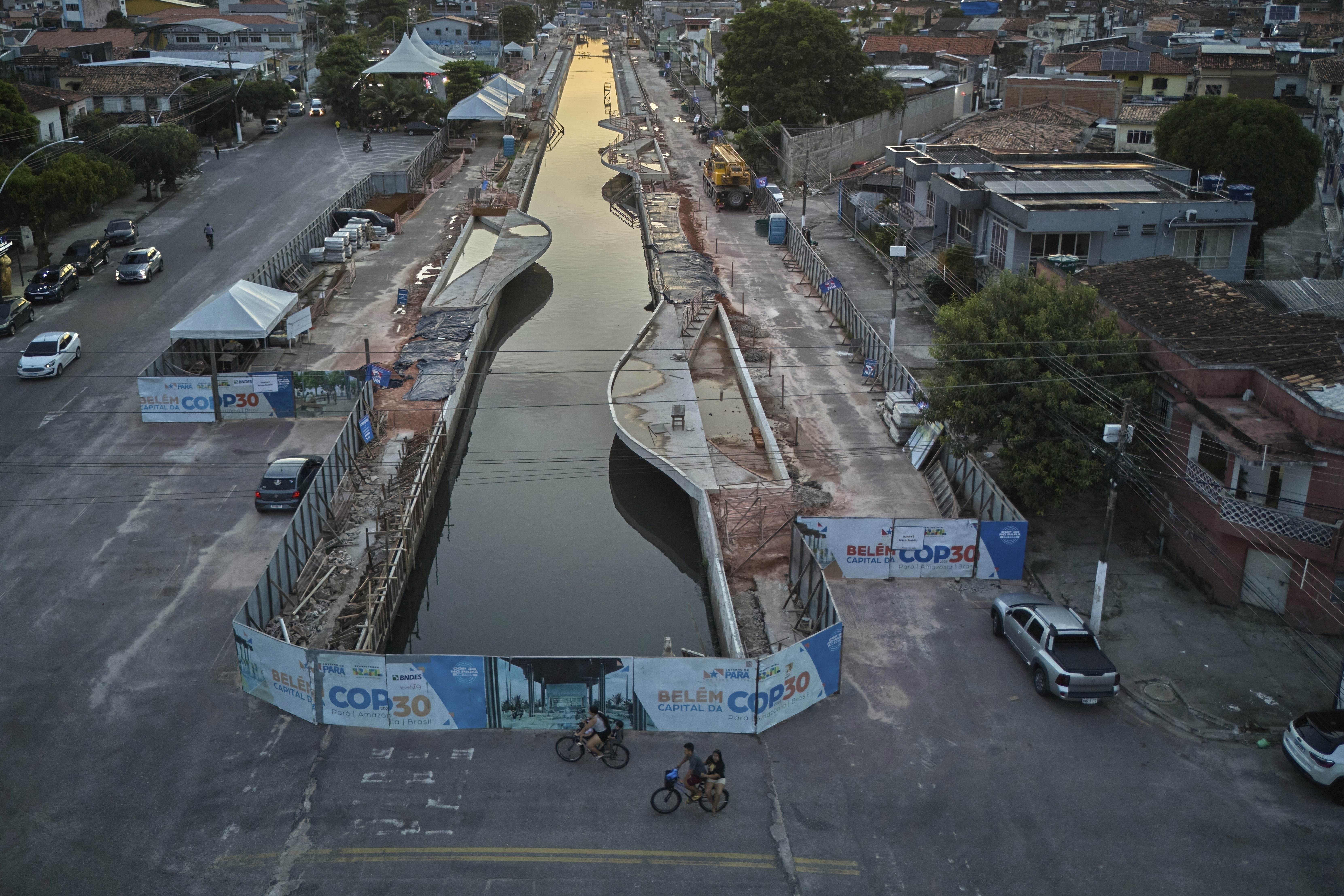 FILE - People ride bikes near signage for the upcoming COP30 U.N. Climate Summit in Belem, Brazil, March 23, 2025. (AP Photo/Jorge Saenz, File)