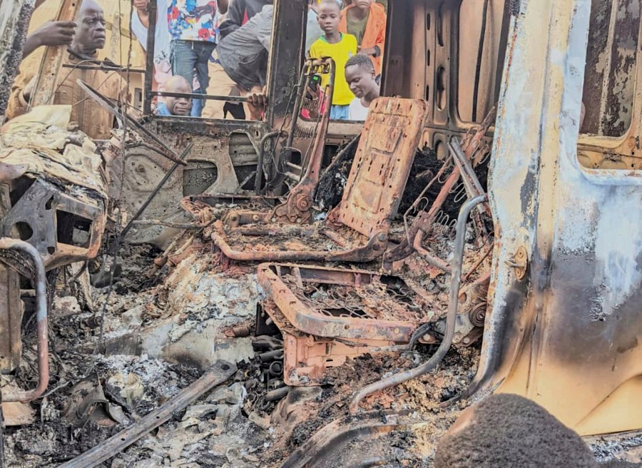 People gather around the charred remains of a burned vehicle following a deadly attack in Komanda, Ituri province of eastern Congo, Sunday, July 27, 2025. (Olivier Okande/UGC via AP)