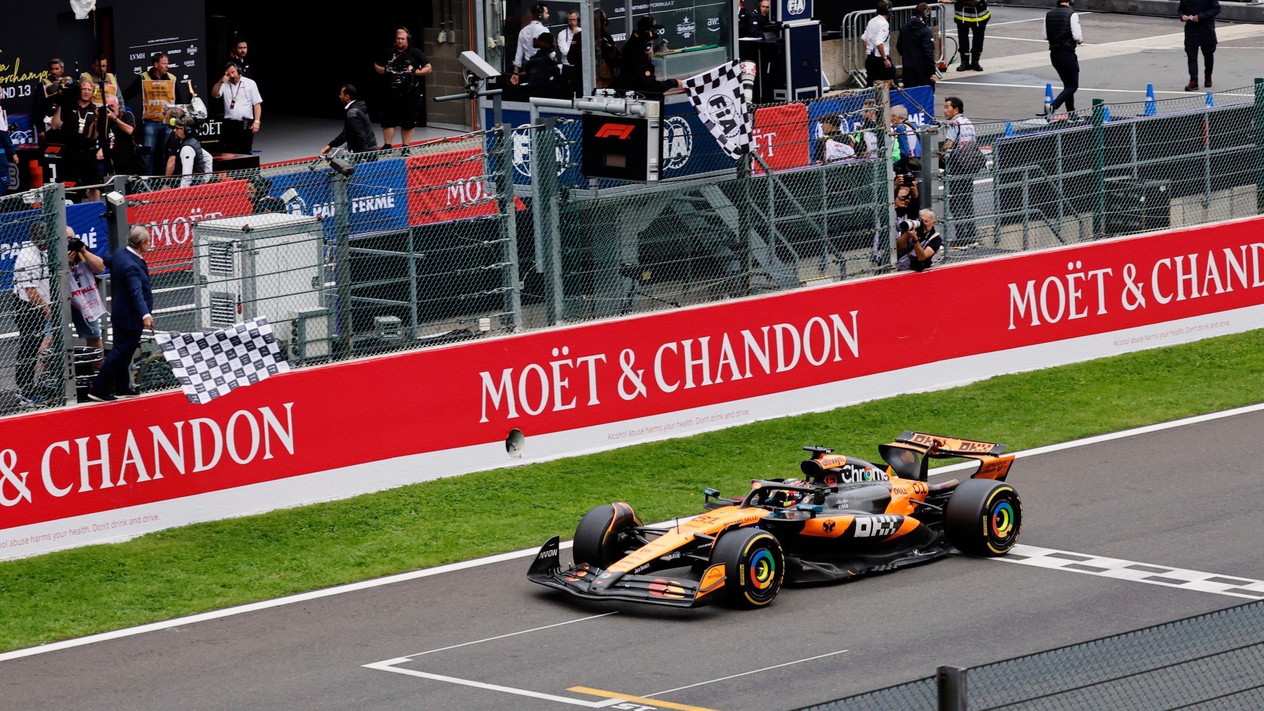 The checkered flag is waved as McLaren driver Oscar Piastri of Australia crosses the finish line to win the Formula One Grand Prix at the Spa-Francorchamps racetrack in Spa, Belgium, Sunday, July 27, 2025. (AP Photo/Geert Vanden Wijngaert)