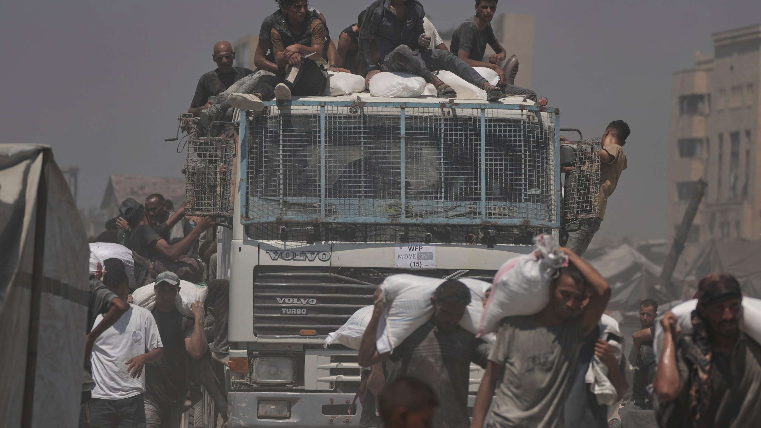 Palestinians carry sacks of flour unloaded from a humanitarian aid convoy that reached Gaza City from the northern Gaza Strip, Sunday, July 27, 2025. (AP Photo/Jehad Alshrafi)