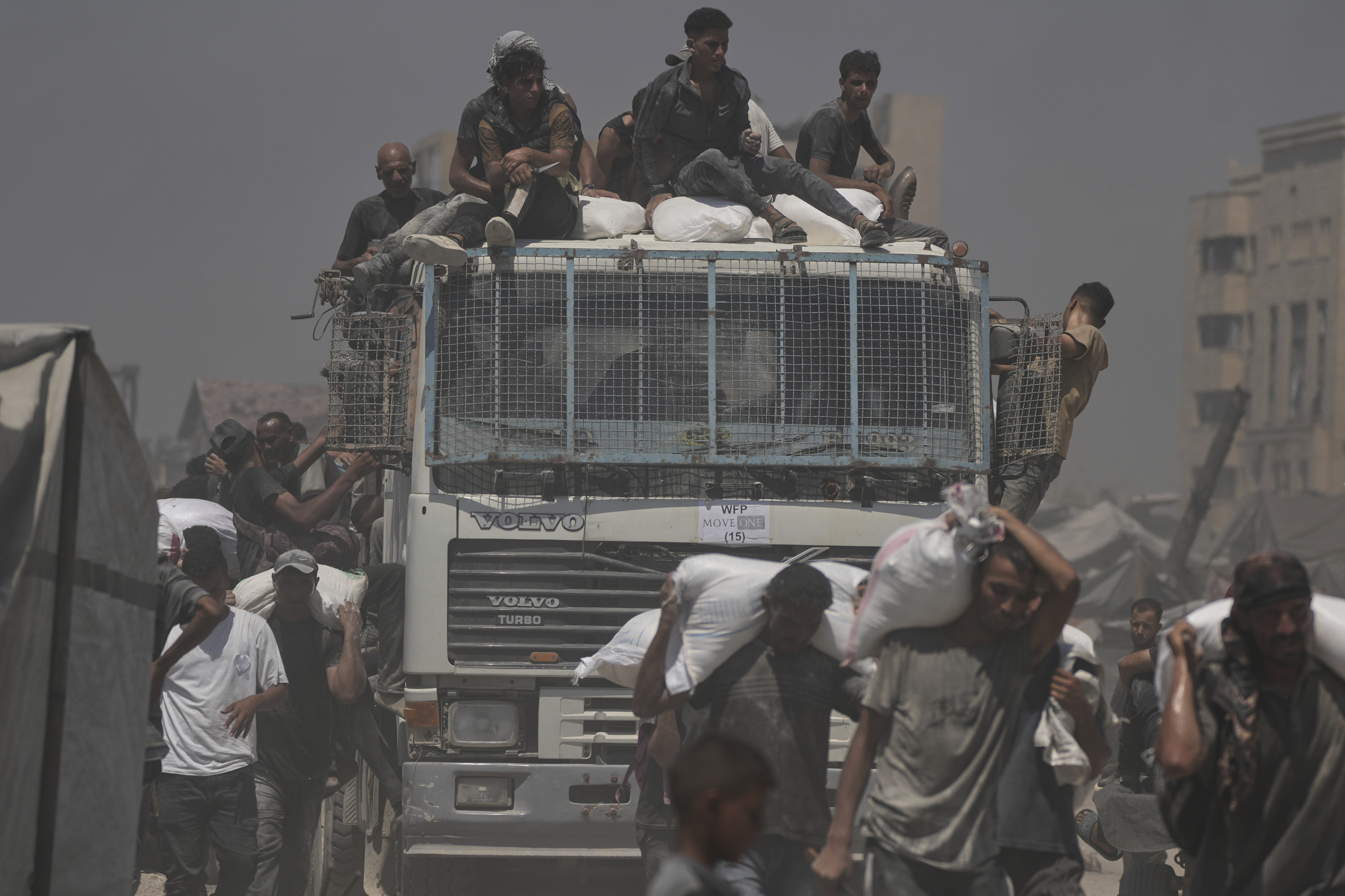 Palestinians carry sacks of flour unloaded from a humanitarian aid convoy that reached Gaza City from the northern Gaza Strip, Sunday, July 27, 2025. (AP Photo/Jehad Alshrafi)