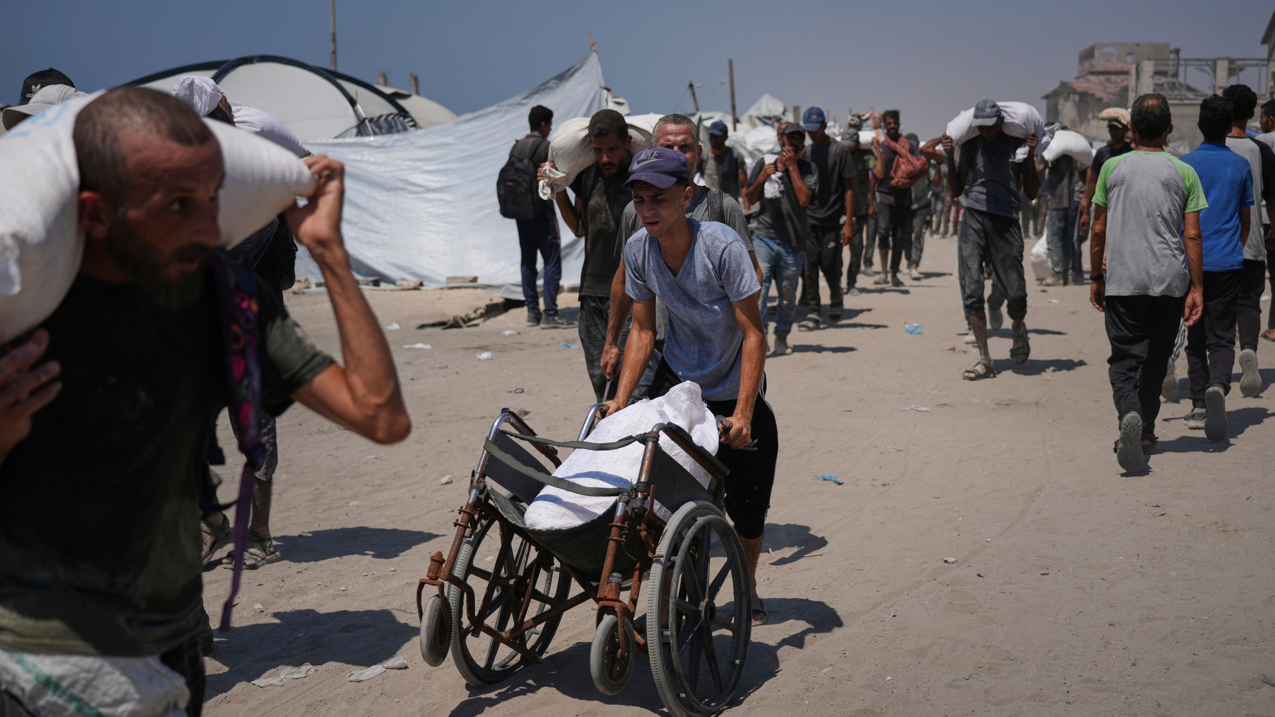 Palestinians carry sacks of flour unloaded from a humanitarian aid convoy that reached Gaza City from the northern Gaza Strip, Sunday, July 27, 2025. (AP Photo/Abdel Kareem Hana)