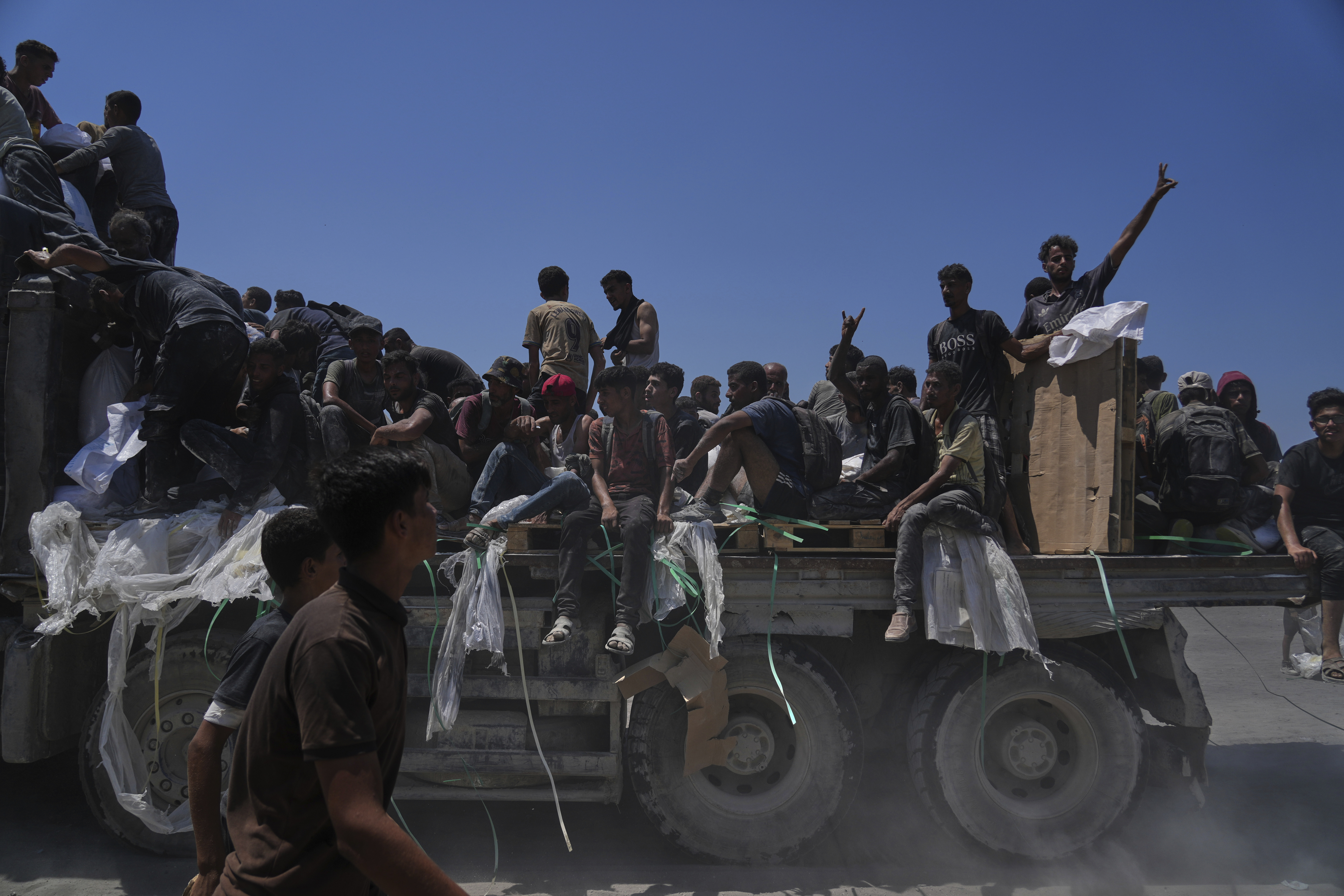 Palestinians hold onto an aid truck returning to Gaza City from the northern Gaza Strip, Sunday, July 27, 2025. (AP Photo/Abdel Kareem Hana)