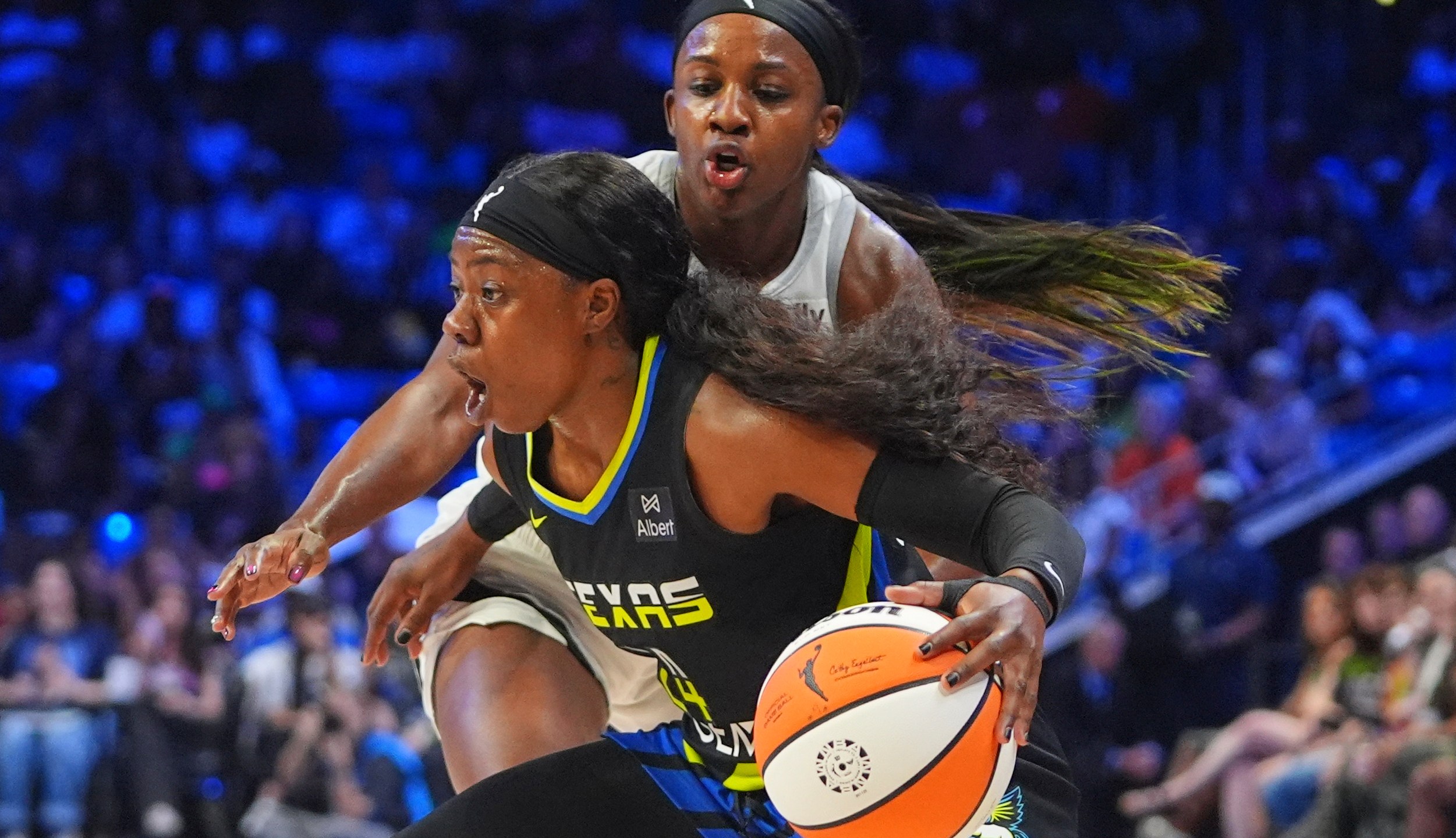 Dallas Wings guard Arike Ogunbowale, front, dribbles against Las Vegas Aces guard Jackie Young, back, during the first half of a WNBA basketball game in Arlington, Texas, Sunday, July 27, 2025. (AP Photo/LM Otero)