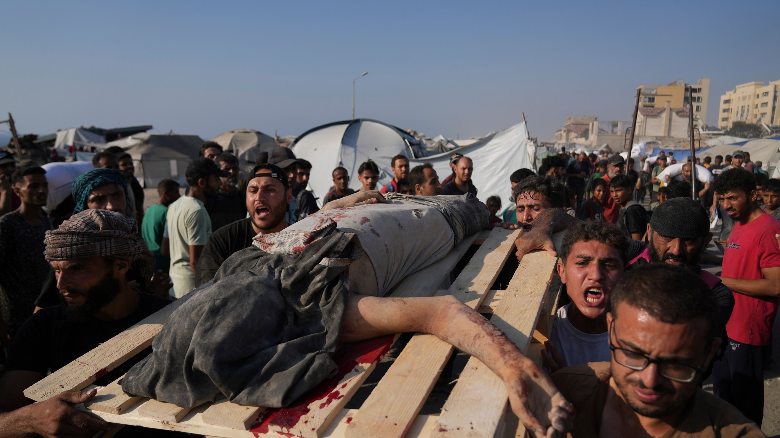 CORRECTS CAUSE OF DEATH Palestinians carry the body of a man who was hit by a truck while attempting to reach a humanitarian aid convoy that entered Gaza City from the northern Gaza Strip, Saturday, July 26, 2025. (AP Photo/Abdel Kareem Hana)