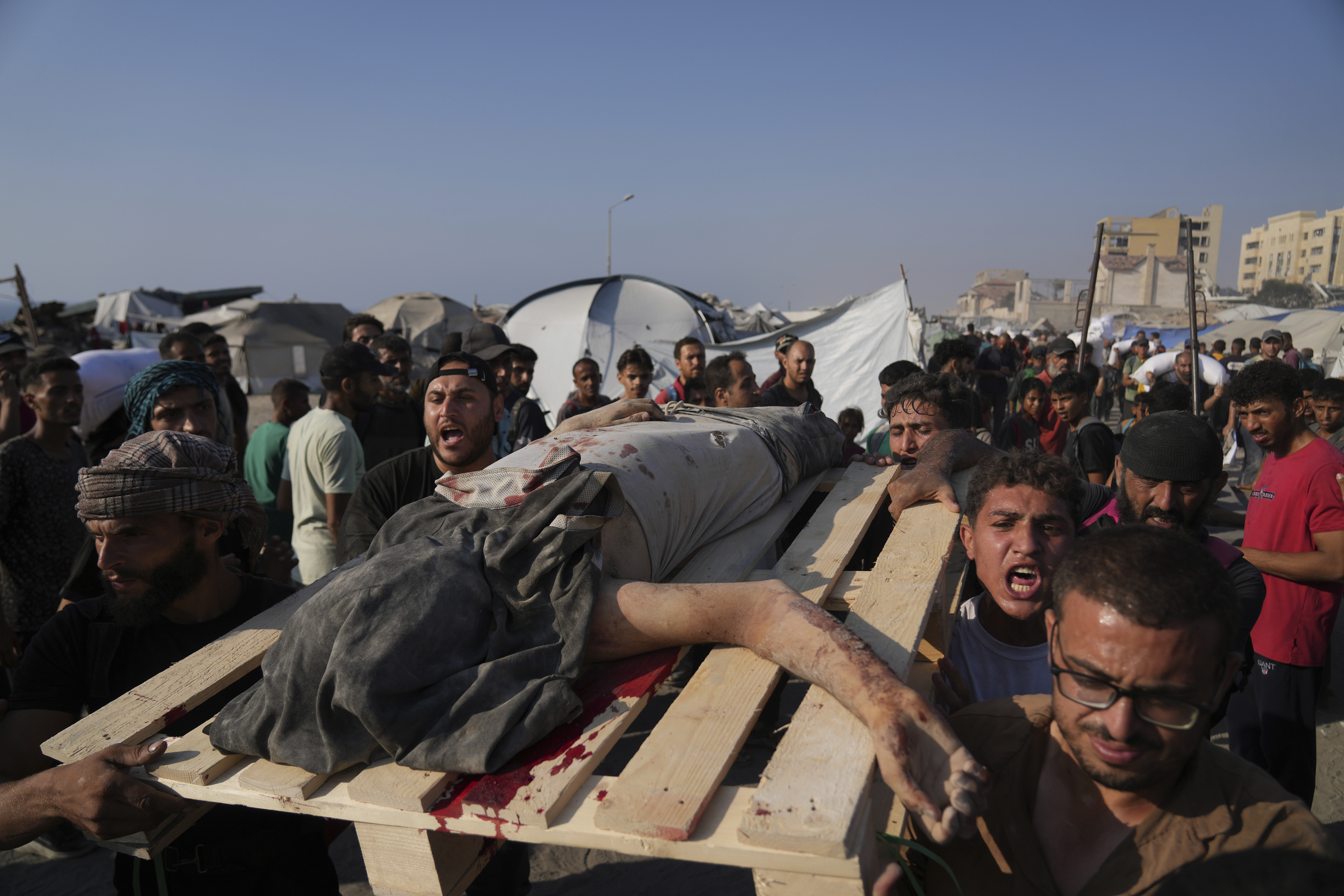 CORRECTS CAUSE OF DEATH Palestinians carry the body of a man who was hit by a truck while attempting to reach a humanitarian aid convoy that entered Gaza City from the northern Gaza Strip, Saturday, July 26, 2025. (AP Photo/Abdel Kareem Hana)