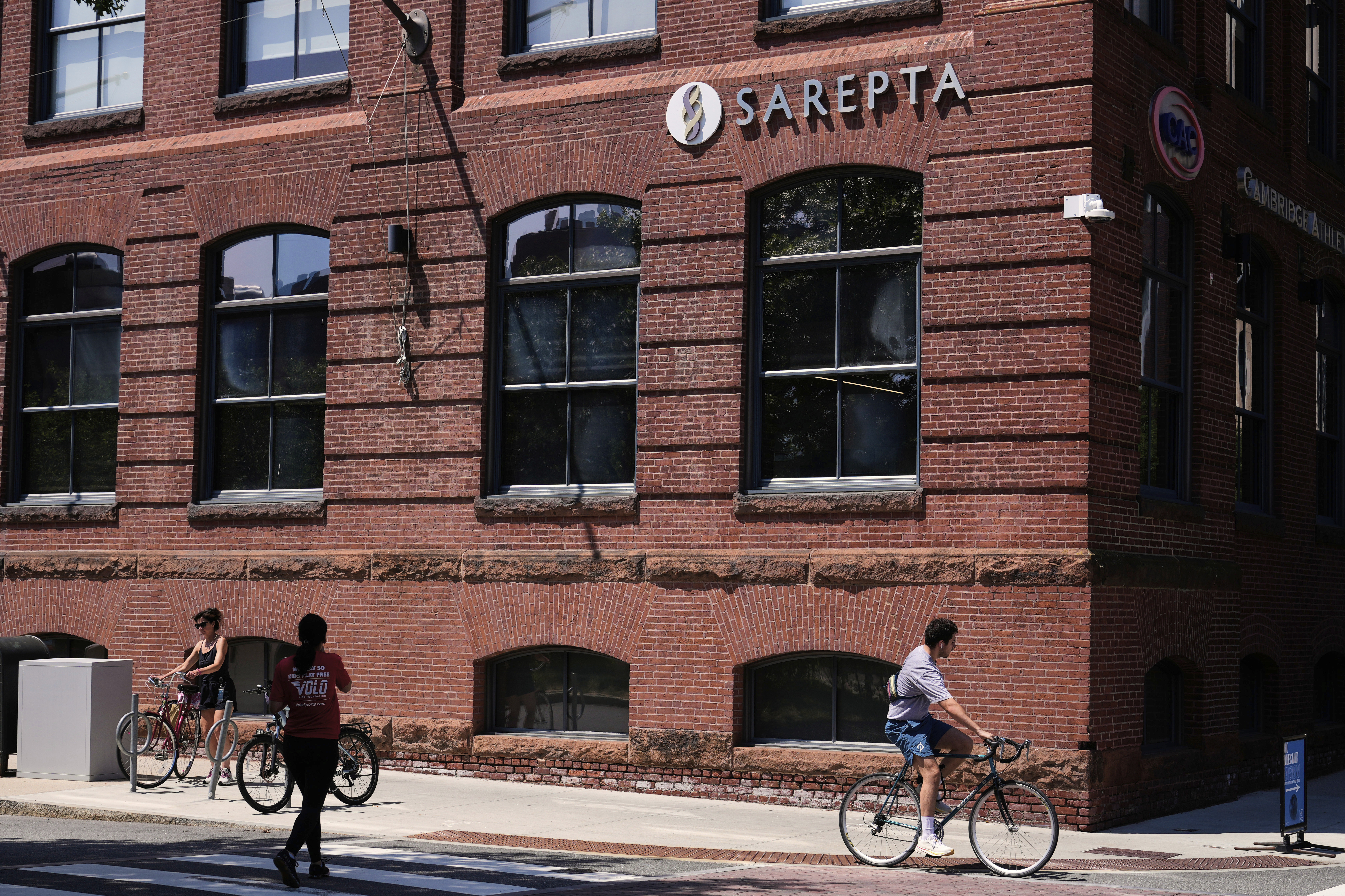 A cyclist passes the headquarters of Sarepta Therapeutics , Monday, July 28, 2025, in Cambridge, Mass. (AP Photo/Charles Krupa)